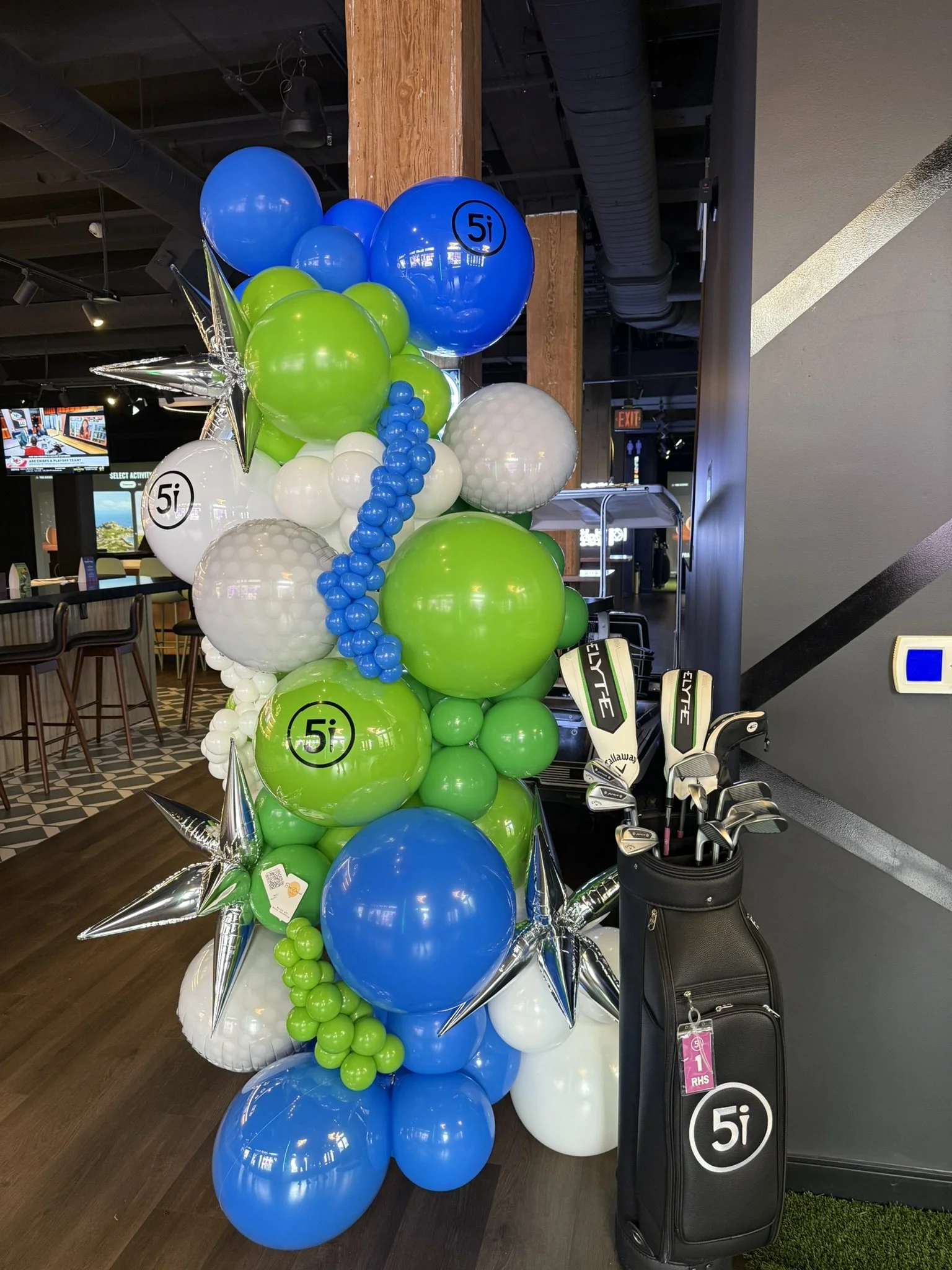 Golf-themed organic balloon tower with green, blue, white, and silver balloons for a corporate event in Boston.