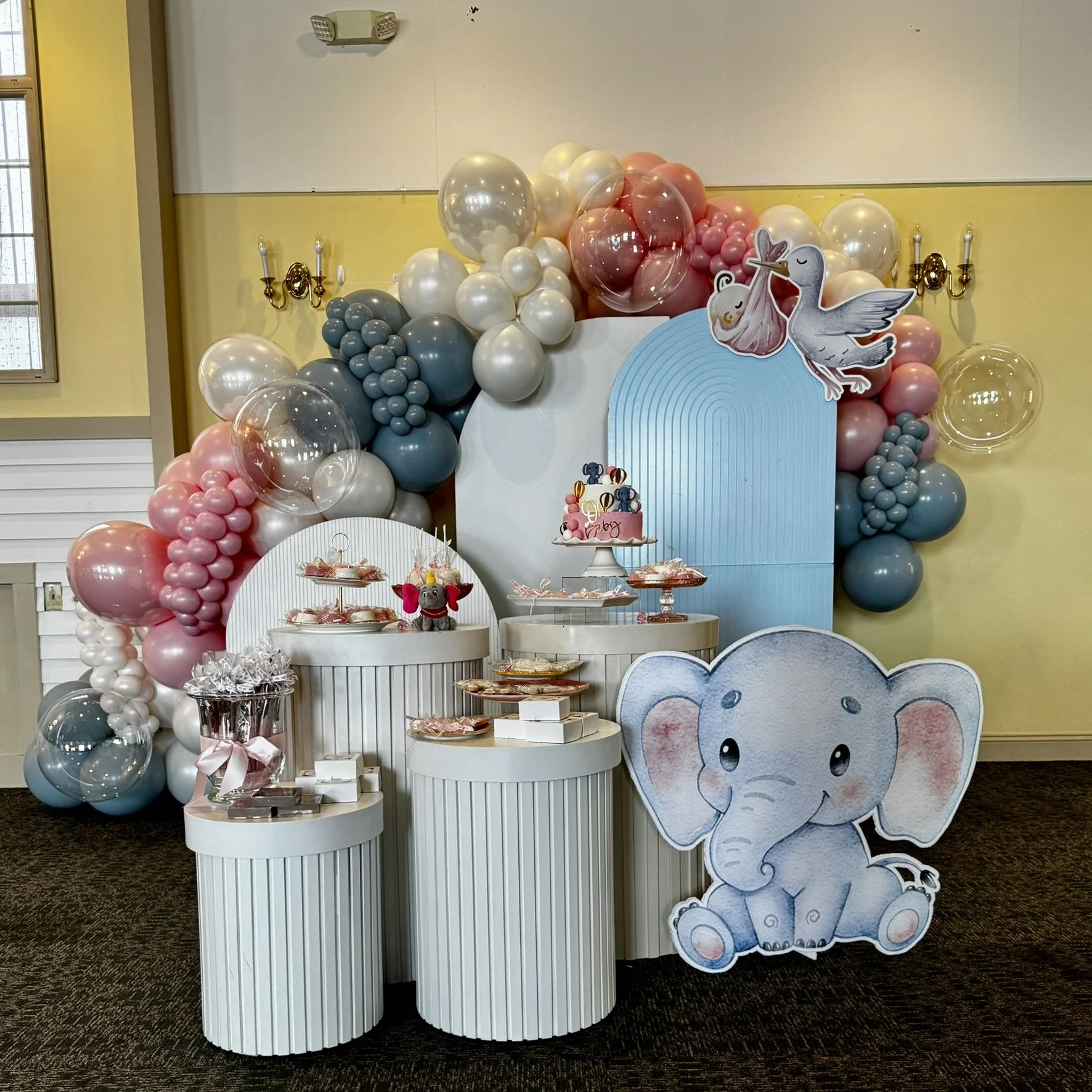 Pastel baby shower balloon arch with elephant theme, cake table, and custom party styling in Boston.