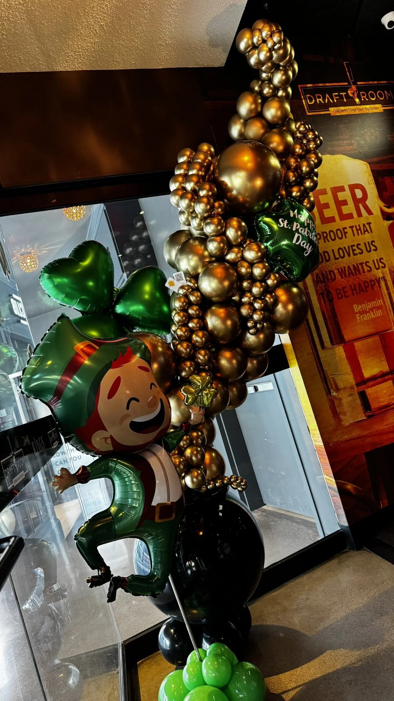 St. Patrick’s Day balloon arch with green, black, and gold balloons, shamrock details, and themed party decor in seaport Boston.