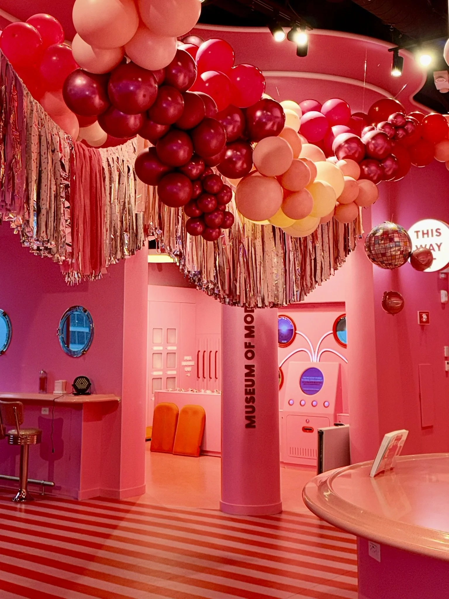 Pink and red balloon ceiling installation with fringe details for a branded event experience at Museum of Ice Cream Boston.