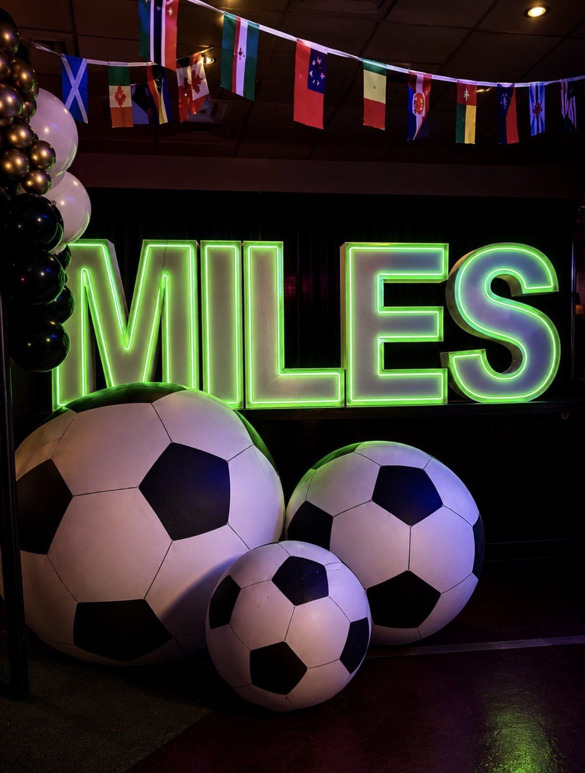 World Cup-inspired Bar Mitzvah decor with a bold illuminated sign, large 4 ft soccer balls, balloon details, and international flags in Boston.