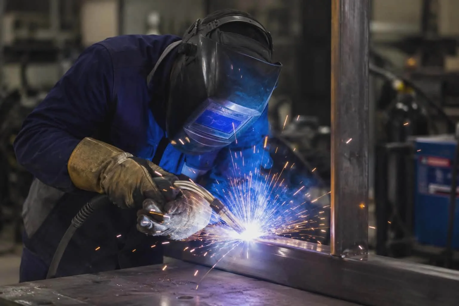 A person welding metal with sparks flying in a workshop.