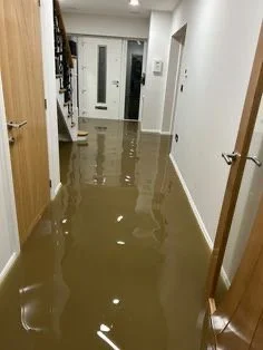 Flooded hallway with water covering the floor and partially submerging doorways in a house.