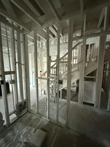 Interior view of a building under construction with exposed wooden framing and staircase