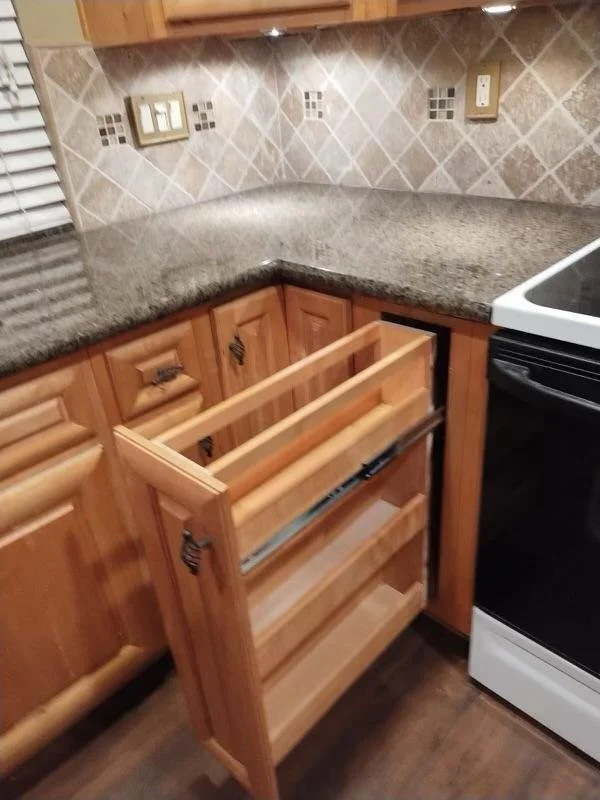 Kitchen corner with wood cabinet drawers, granite countertop, tiled backsplash, and a partial view of a white oven.