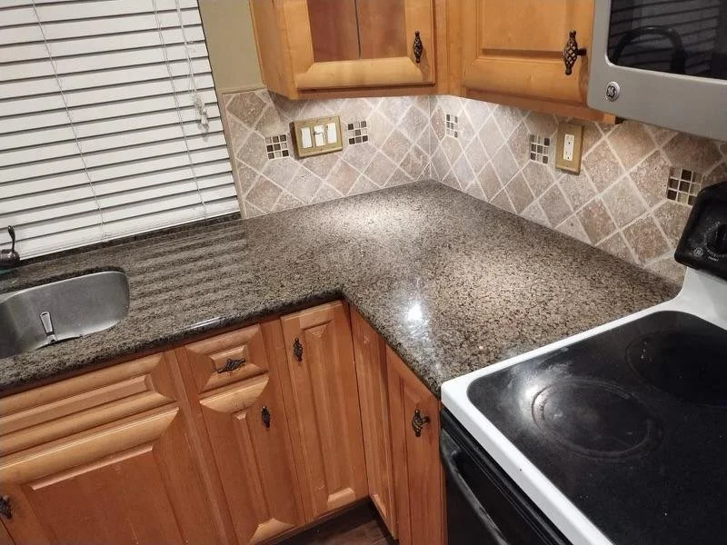 Kitchen countertop with a small sink, wooden cabinets, and a stove in a residential kitchen.