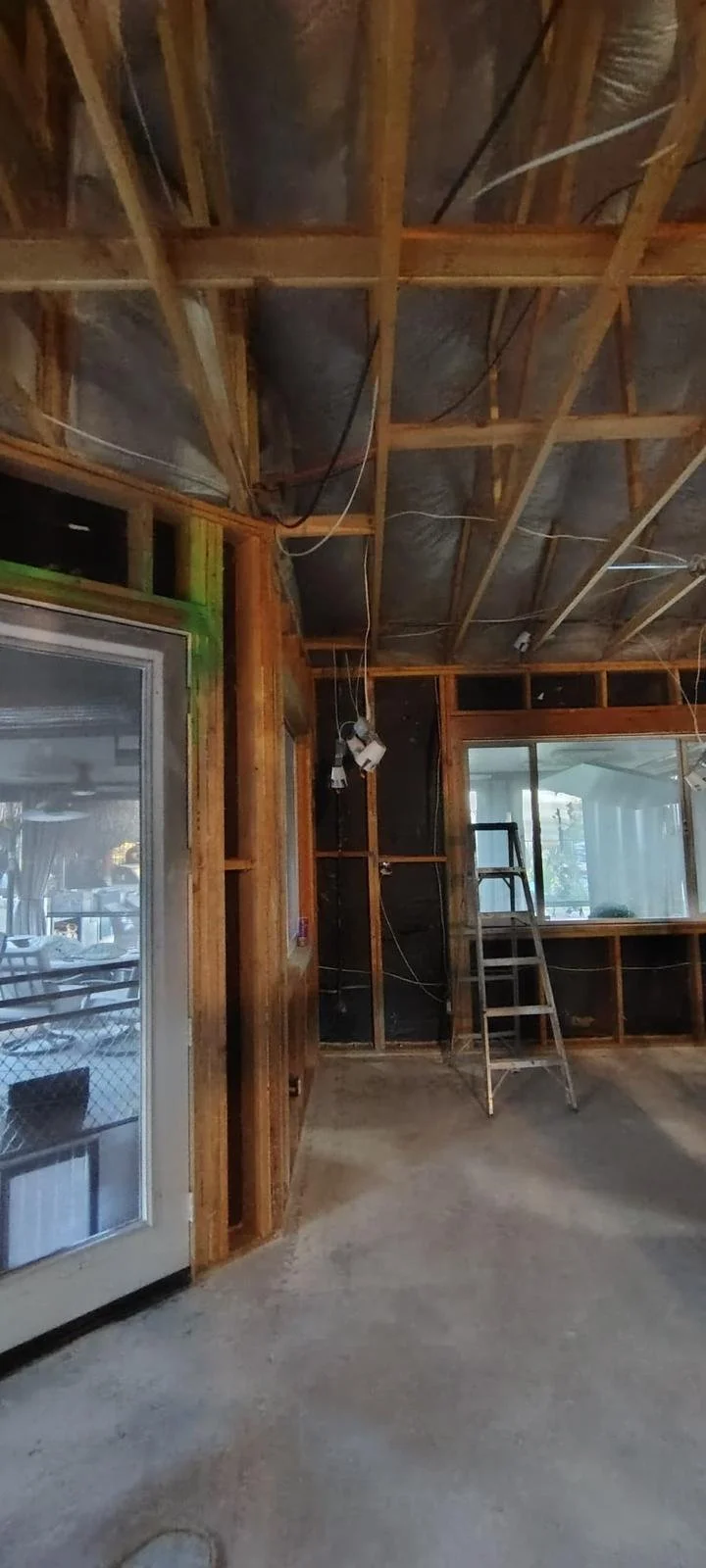 Interior of a room under construction or renovation with exposed wooden framing, a ladder, and unfinished walls and ceiling.