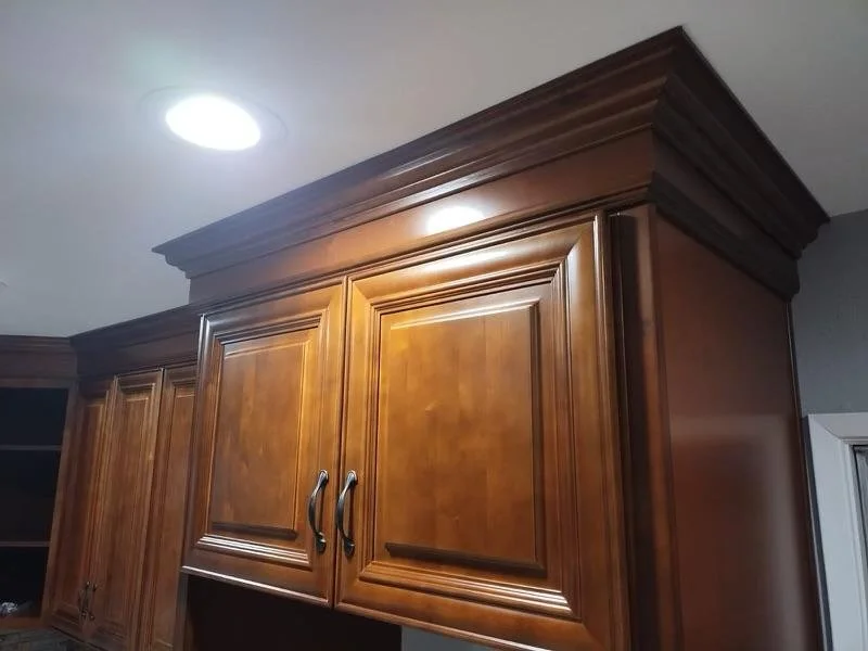 Close-up of wood kitchen cabinets with crown molding in a home interior.