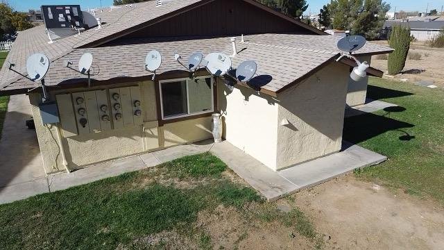 View of a house roof with multiple satellite dishes attached all around the roof edge.