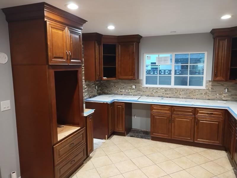 Kitchen with wooden cabinets, a tiled backsplash, and a large window above the countertops.