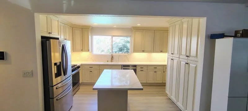 Kitchen with beige cabinets, a large window above the sink, a central island, and stainless steel appliances.