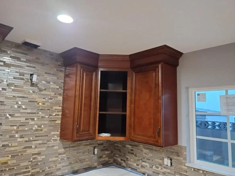 Kitchen with wooden cabinets and a mosaic tile backsplash, window showing an outdoor view.