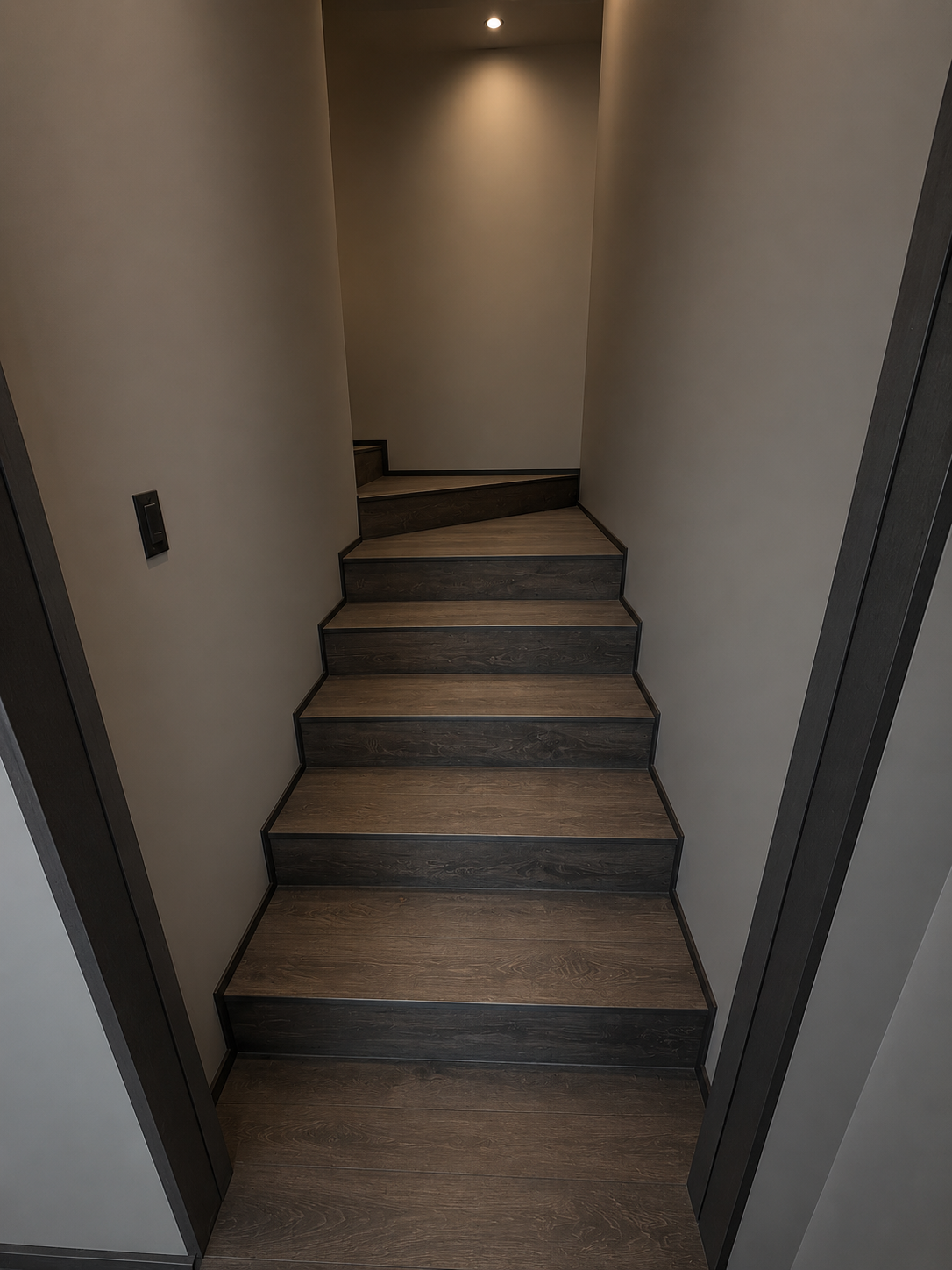 Indoor staircase with dark wood steps and light-colored walls, leading upstairs, with a small ceiling light.