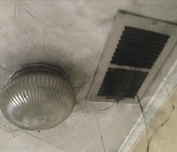 Ceiling vent and light fixture covered in dust and spiderwebs.