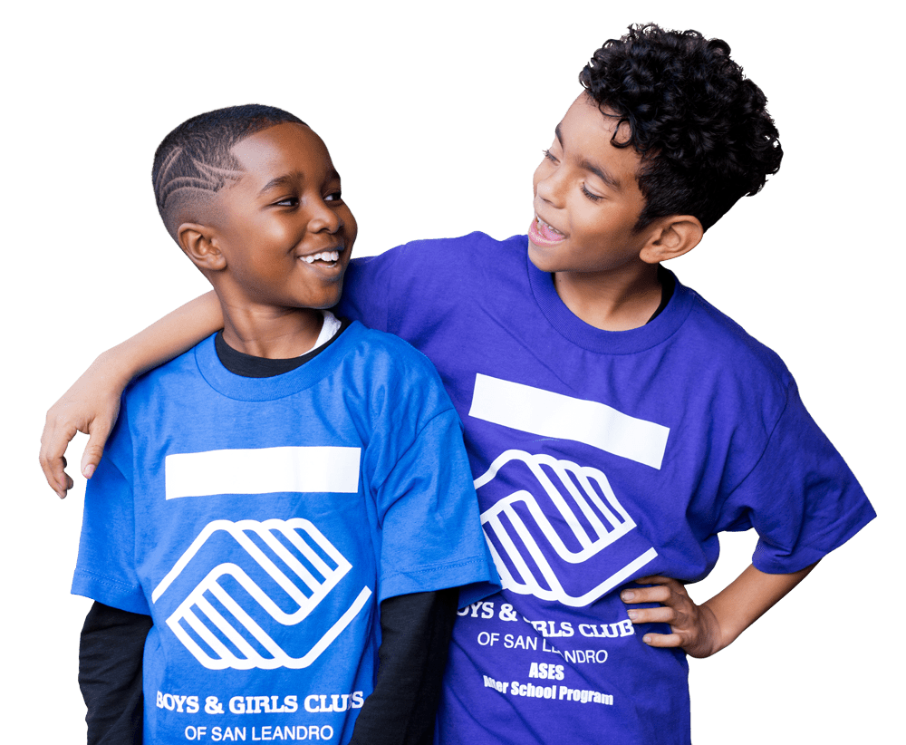 Two boys wearing matching blue T-shirts with white logos, smiling and standing close with one boy's arm around the other.