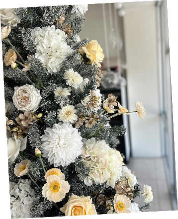 Close-up of a decorated Christmas tree with white and cream-colored flowers and ornaments, set indoors.