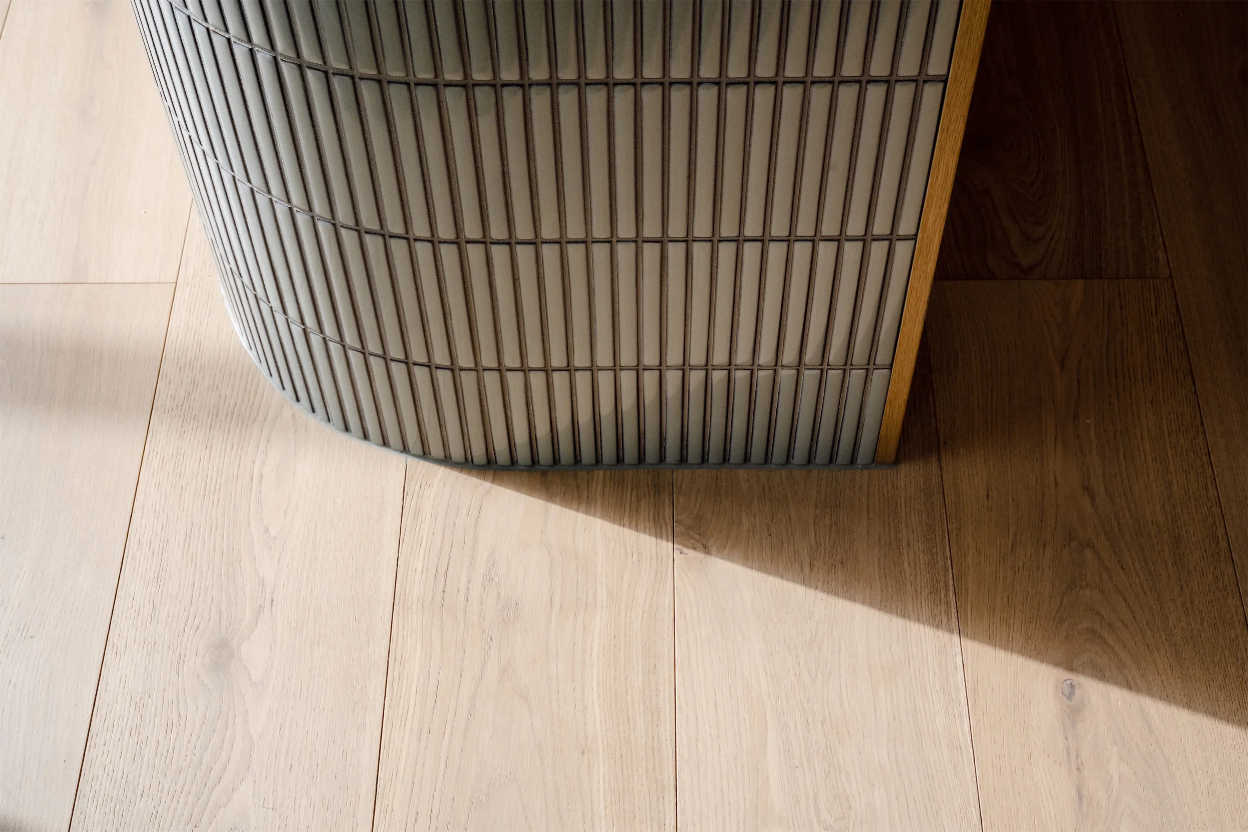 Close-up of a piece of furniture with a wooden frame and a grid-patterned surface, placed on a light-colored wooden floor.