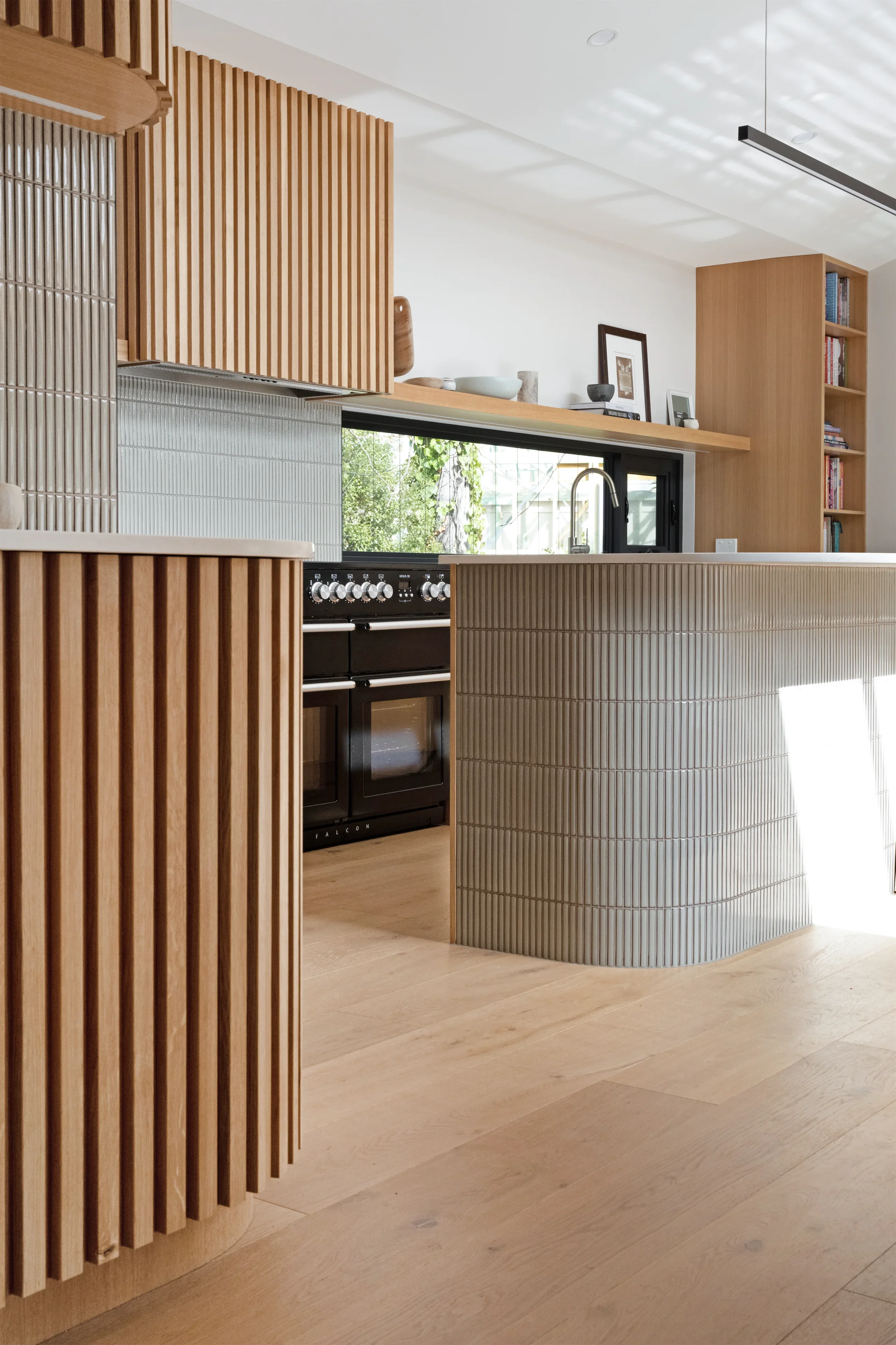 Modern kitchen with wooden accents, black oven, light wood flooring, and a large window.