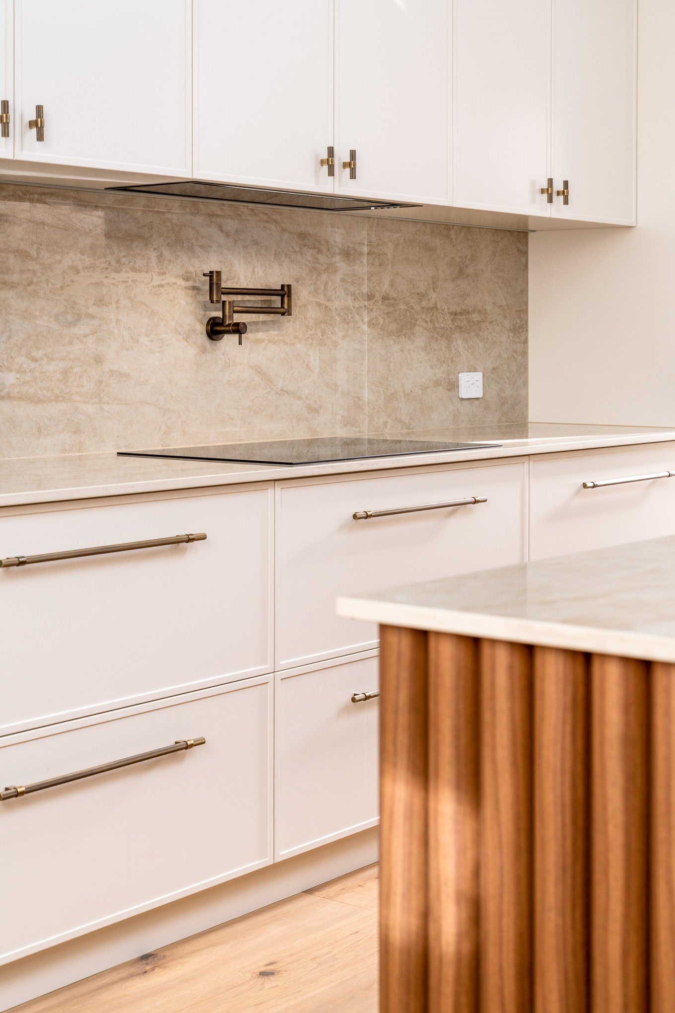 Modern kitchen with white cabinets, a beige marble backsplash, and a wooden island.