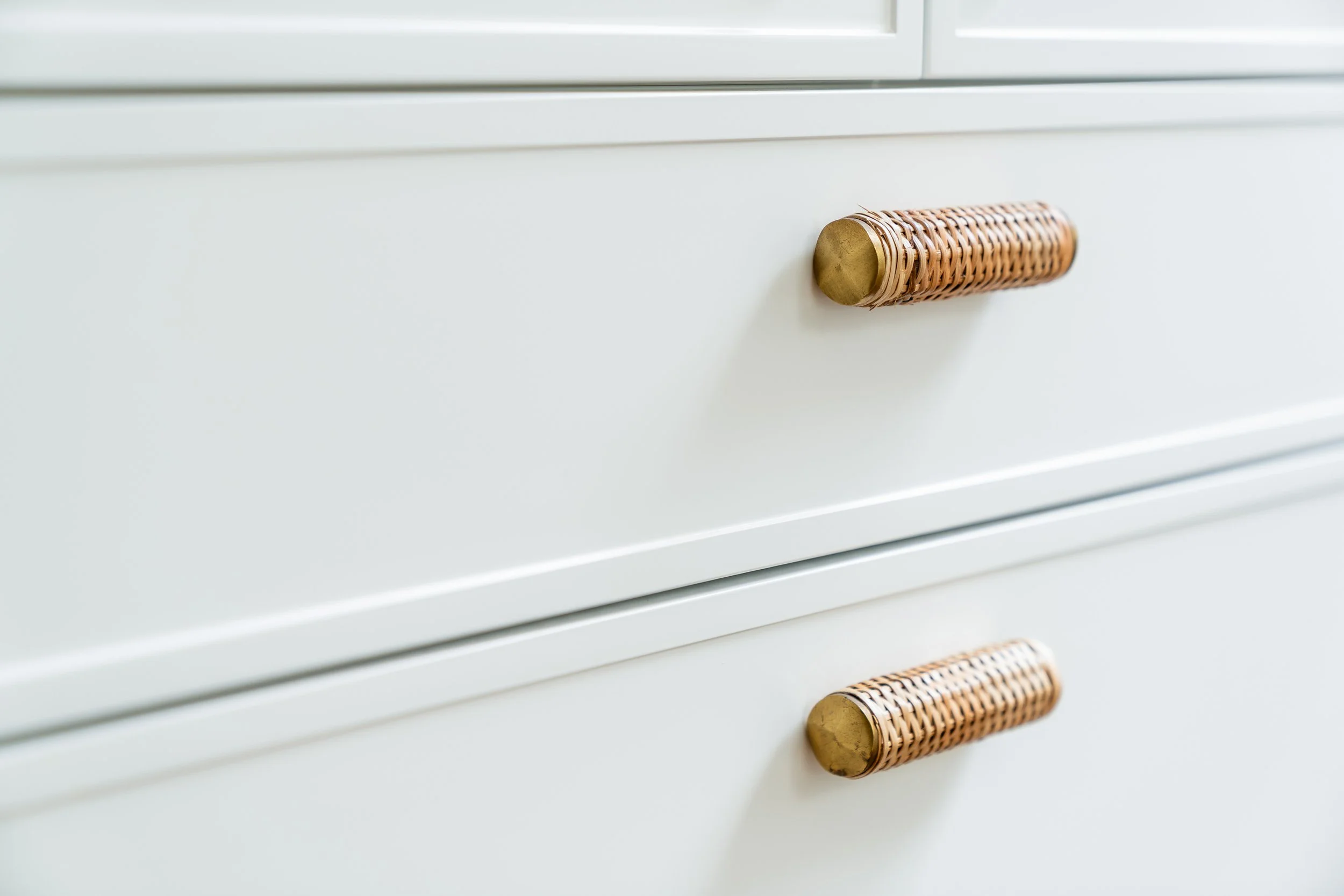 Close-up image of a white dresser with woven handles.