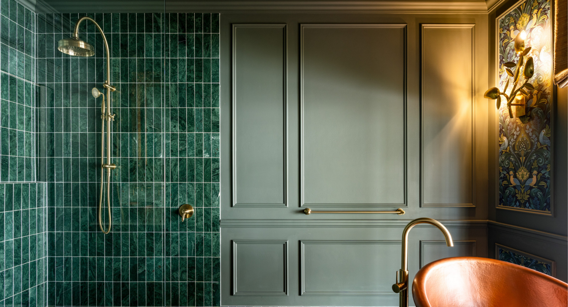 Interior of a bathroom with green tiled shower area, gold fixtures, and decorative wallpaper on the wall.