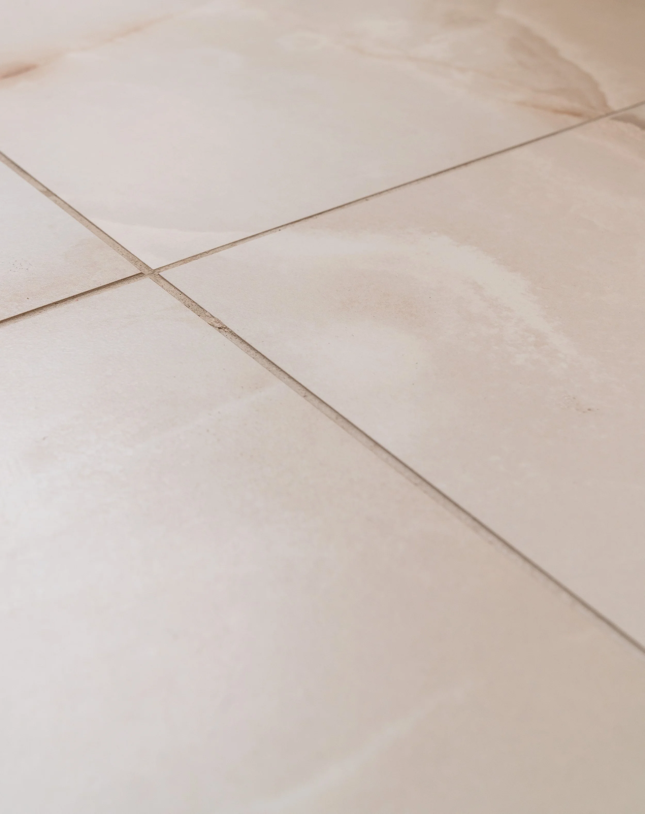 Close-up of beige ceramic floor tiles with grout lines.
