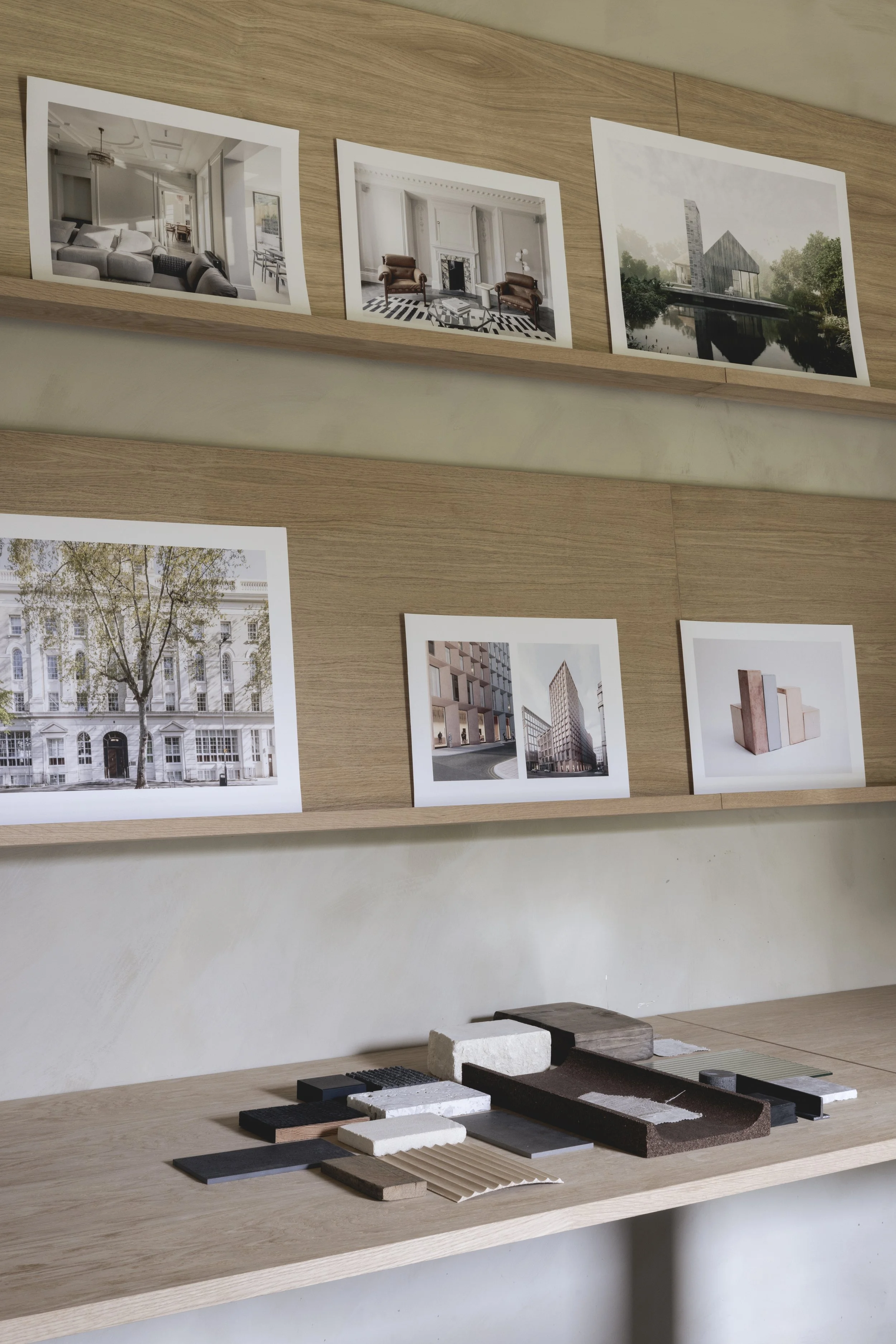Display table with architectural design samples, fabric swatches, and photographs of interior and exterior buildings on the wall.