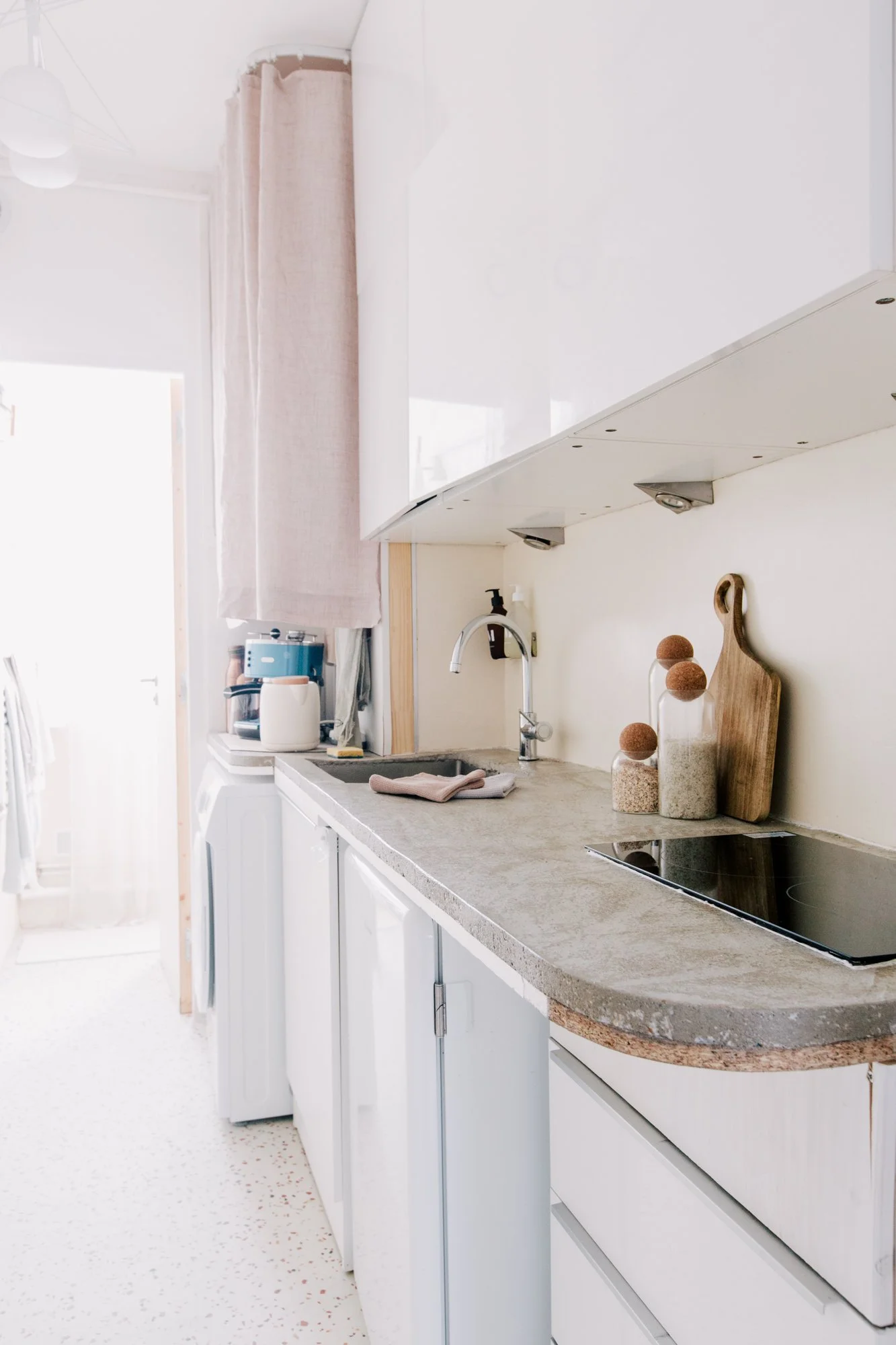 Cuisine moderne blanchie avec plan de travail en granite, vaisselle, herbes et accessoires décoratifs sur le comptoir.