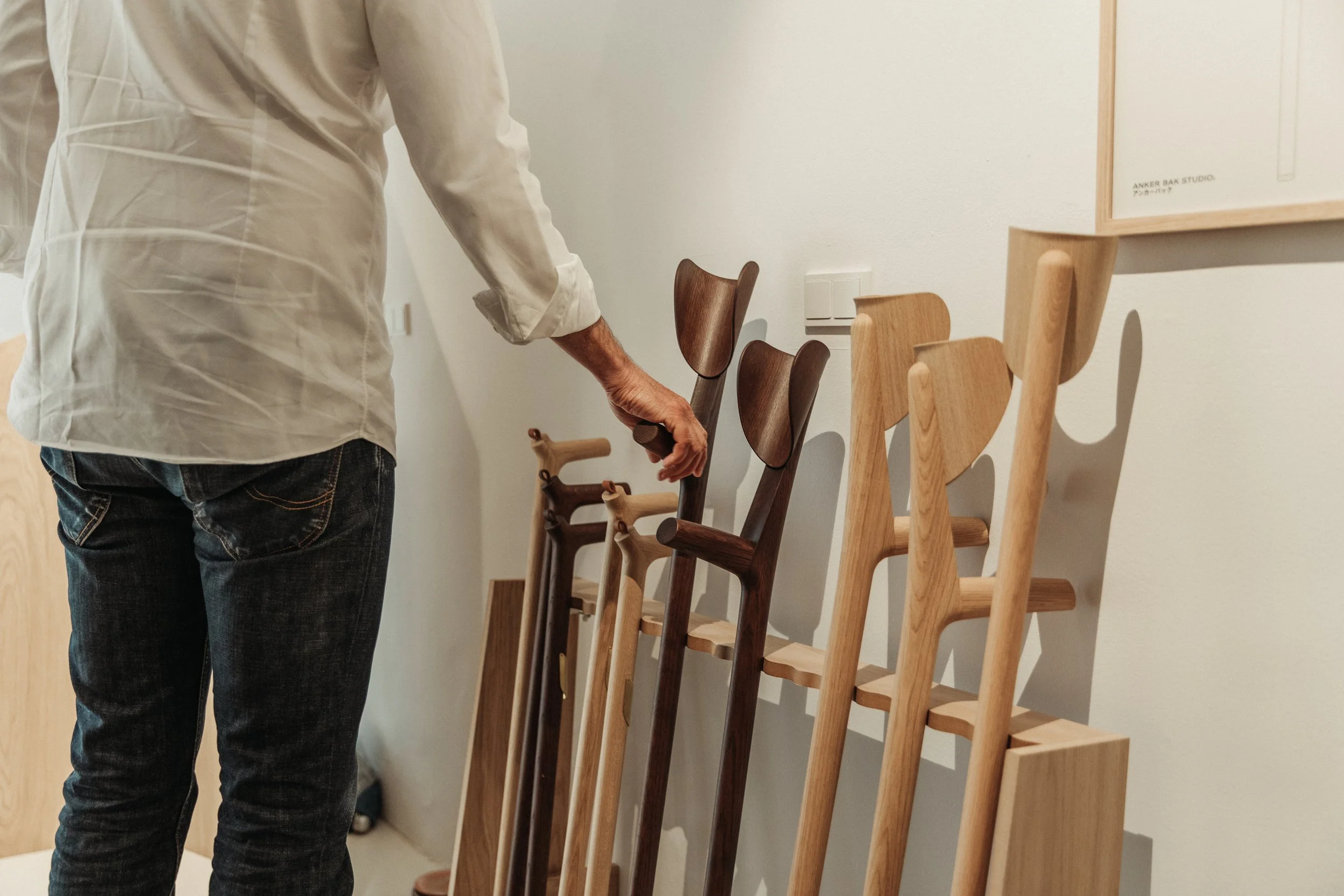 Person viewing a display of wooden chairs in a furniture store.