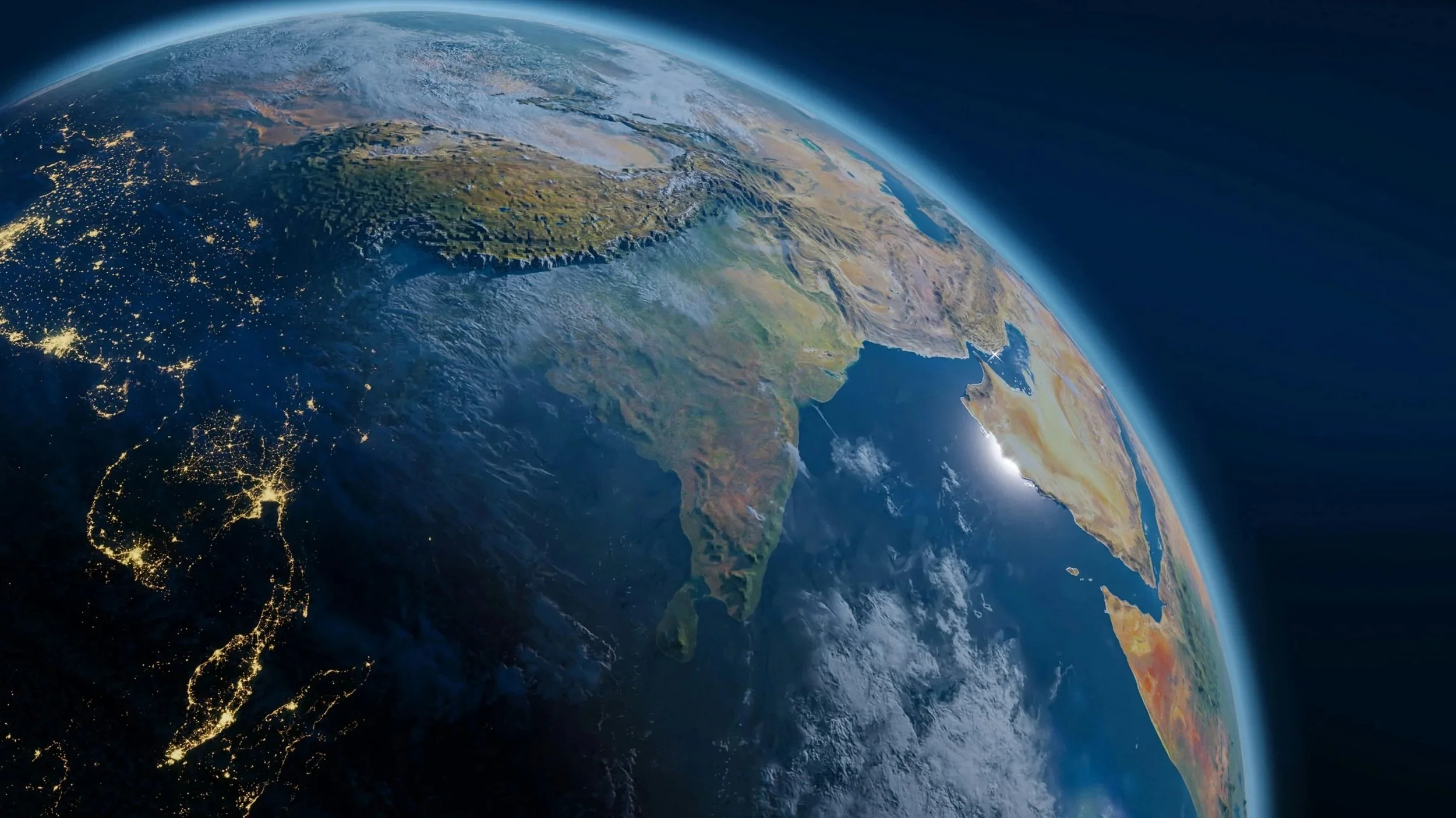 View of Earth from space showing the continent of Australia, New Zealand, and parts of Indonesia and Southeast Asia, with city lights visible at night and a curved horizon showing Earth's atmosphere.
