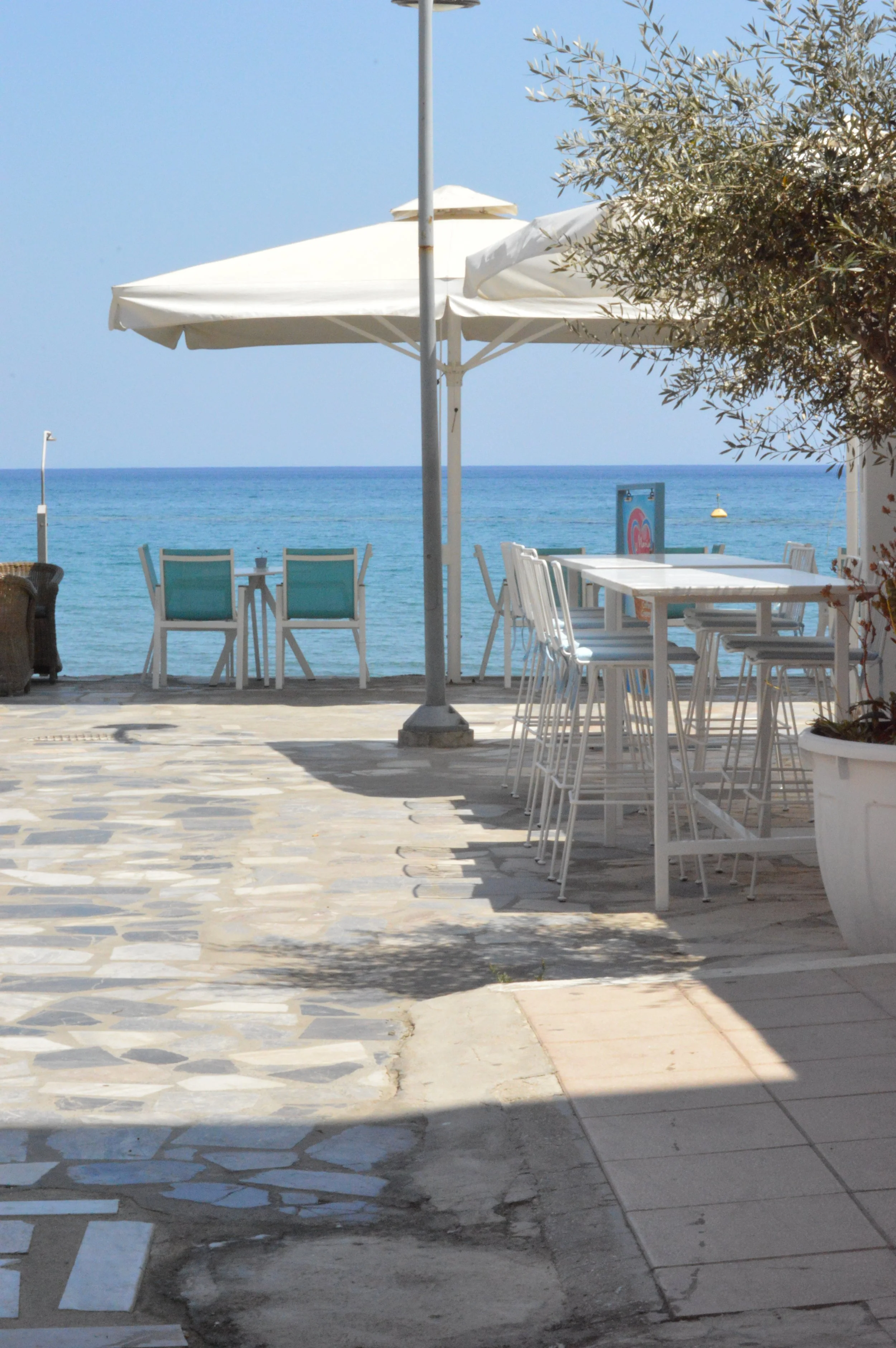 Gelateria Maria - A seaside outdoor restaurant with white tables and chairs, parasols, and a view of the ocean.