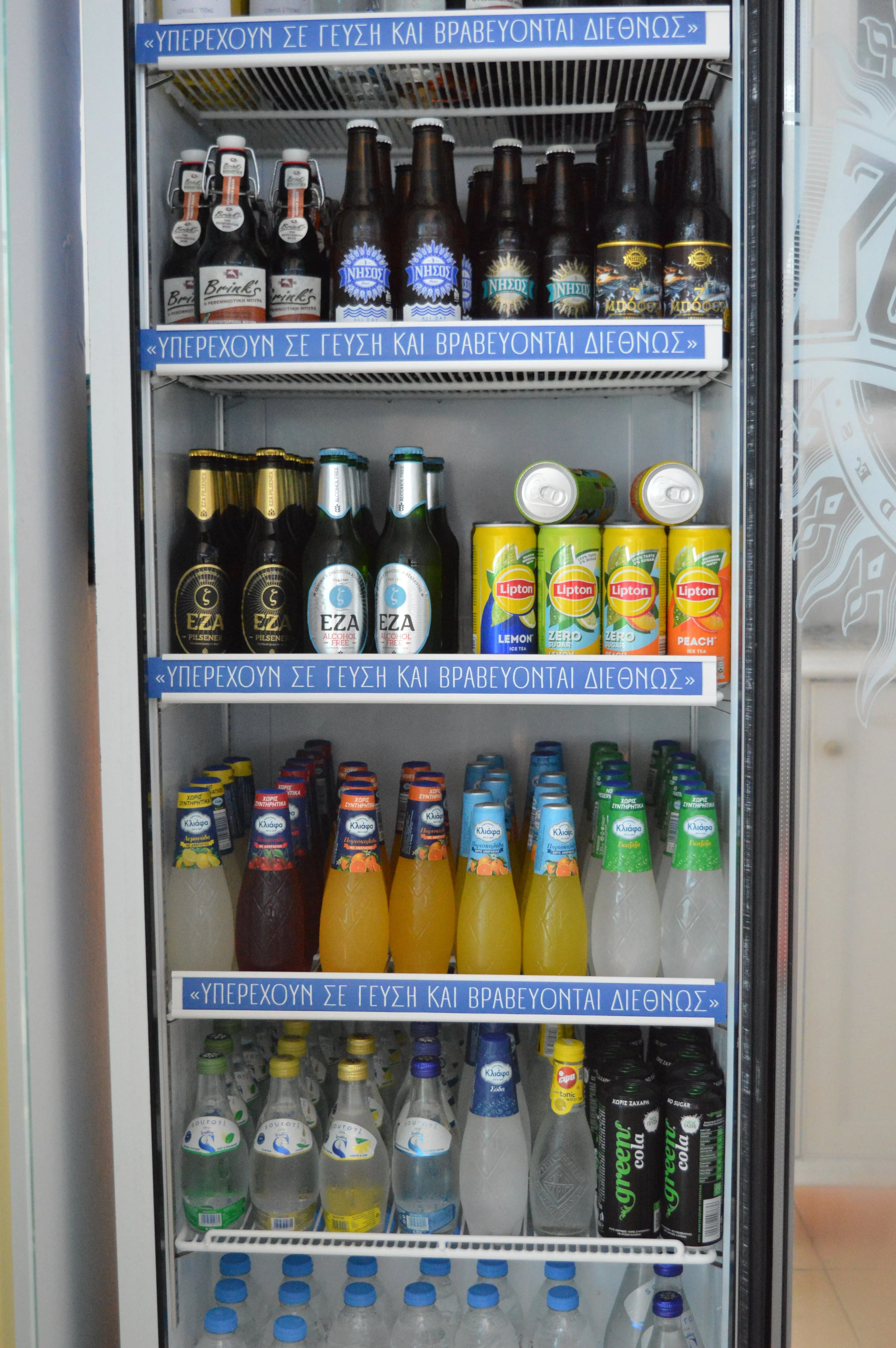 Gelateria Maria - A refrigerator filled with various bottled and canned beverages, including beers, soft drinks, and fruit juices, organized on multiple shelves.