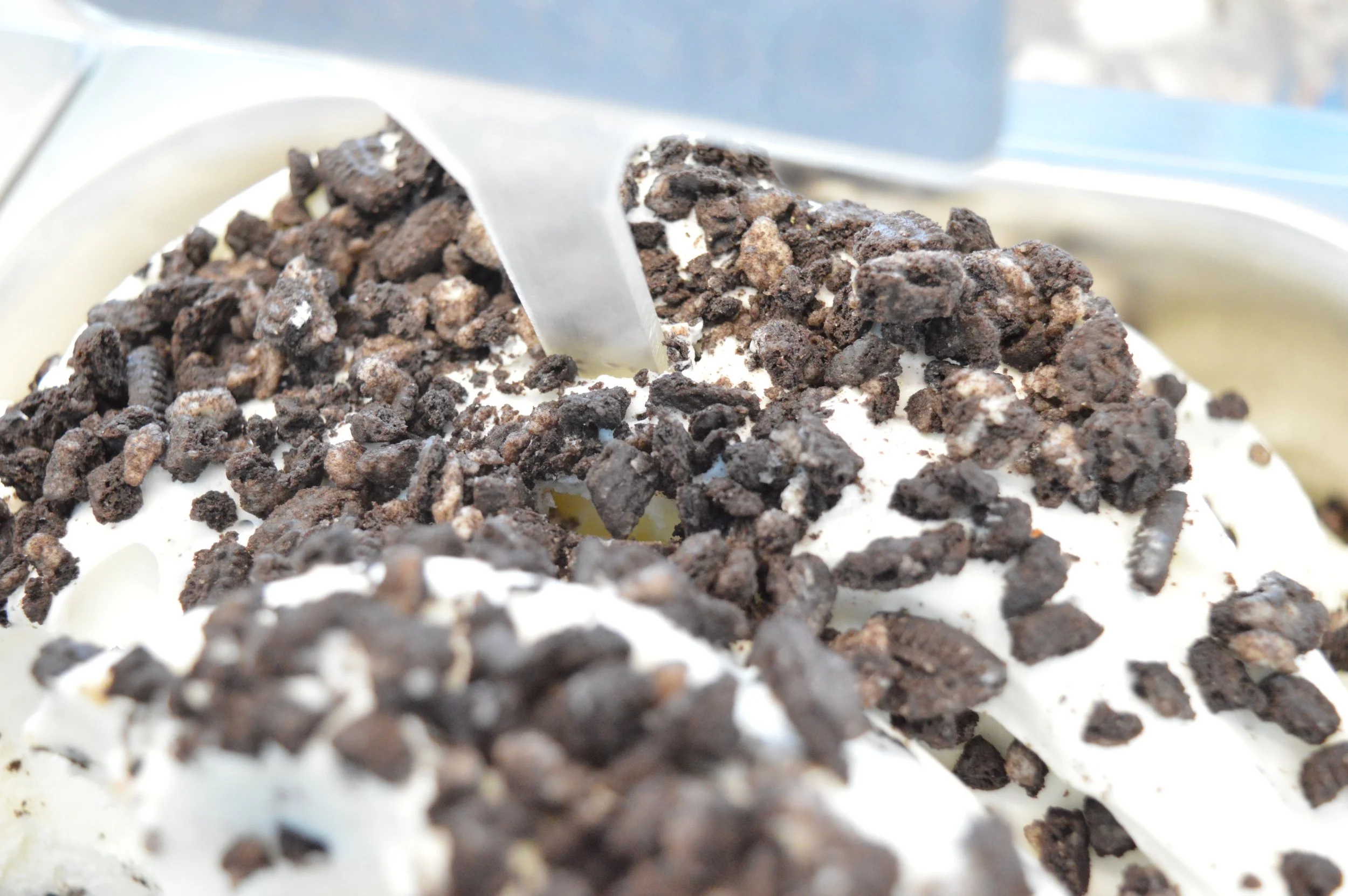 Gelateria Maria - Close-up of a chocolate and vanilla ice cream with crumbled Oreo cookies and chocolate cookie pieces sprinkled on top.