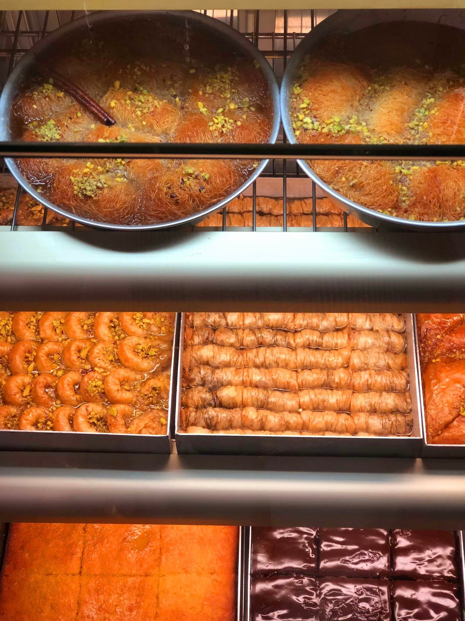 Gelateria Maria - Various Middle Eastern desserts displayed in trays, including baklava, date-filled rolls, and prawns, with a view from above.