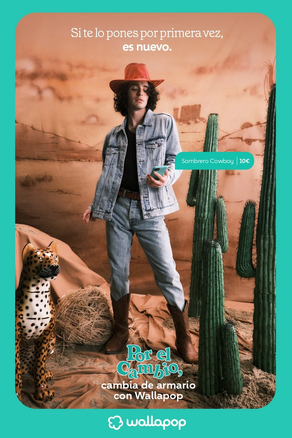 A woman dressed as a cowboy in a desert scene with cacti, a cheetah statue, and a hay bale, holding a smartphone, promoting a cowboy hat priced at 10 euros, with Spanish text about wardrobe change with Wallapop.