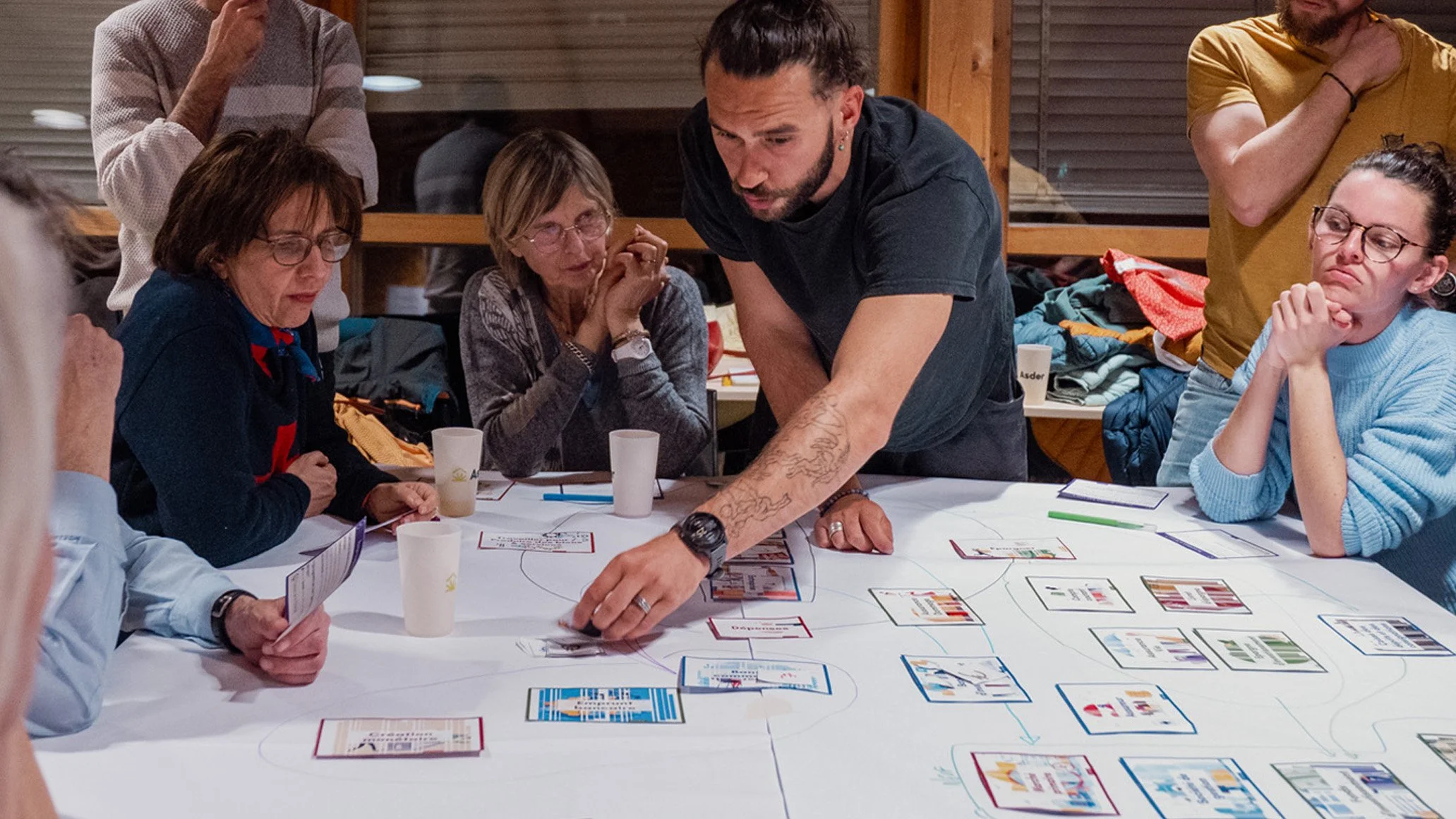 Groupe de personnes autour d'une table, discutant et analysant des cartes liées à la fresque de la finance.