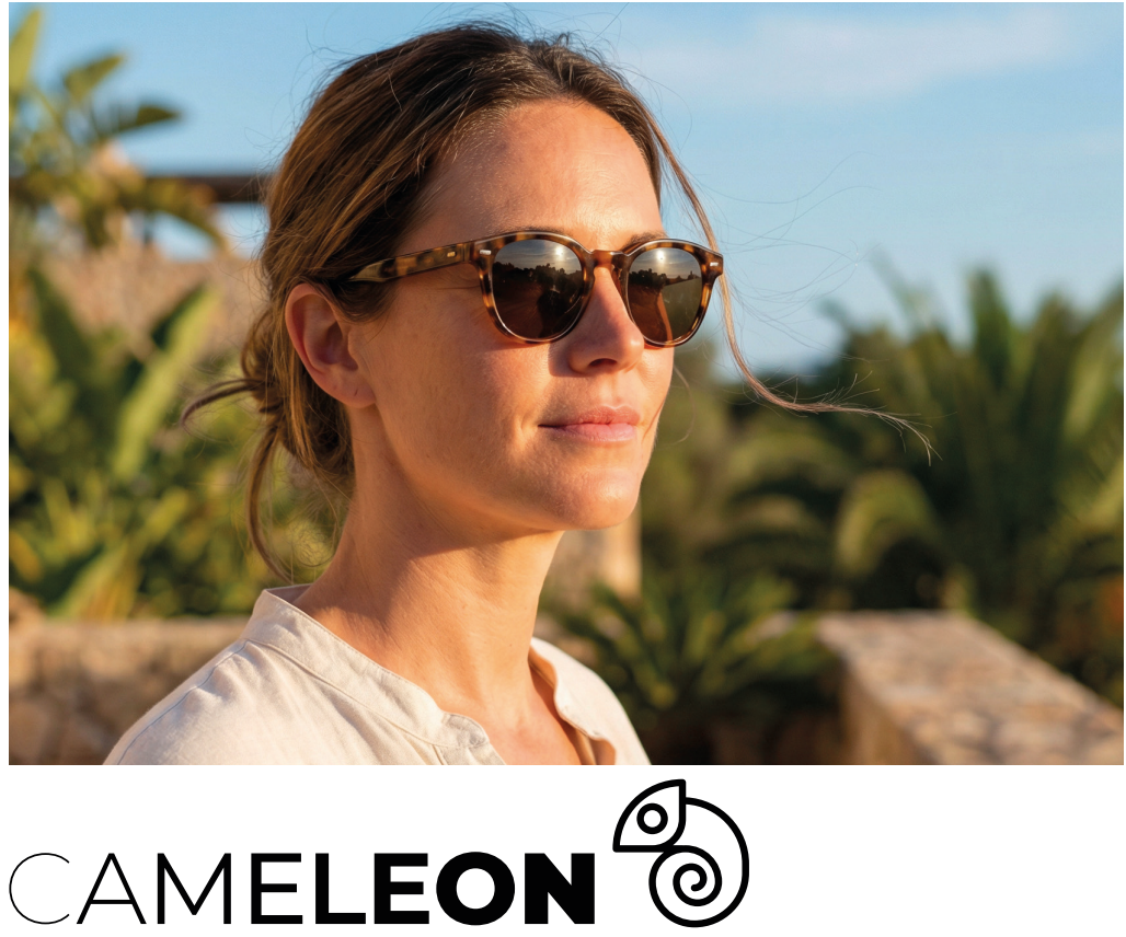 A woman with sunglasses looking into the distance outside with greenery in the background.