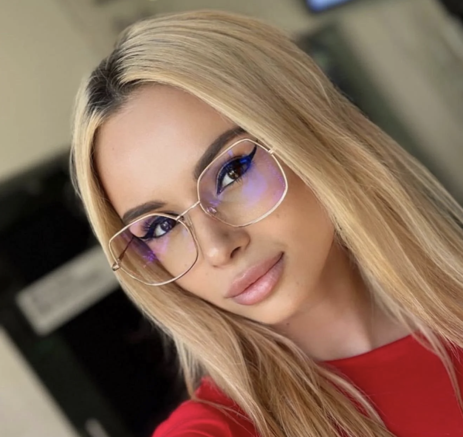 A woman with blonde hair, glasses, and wearing a red top.