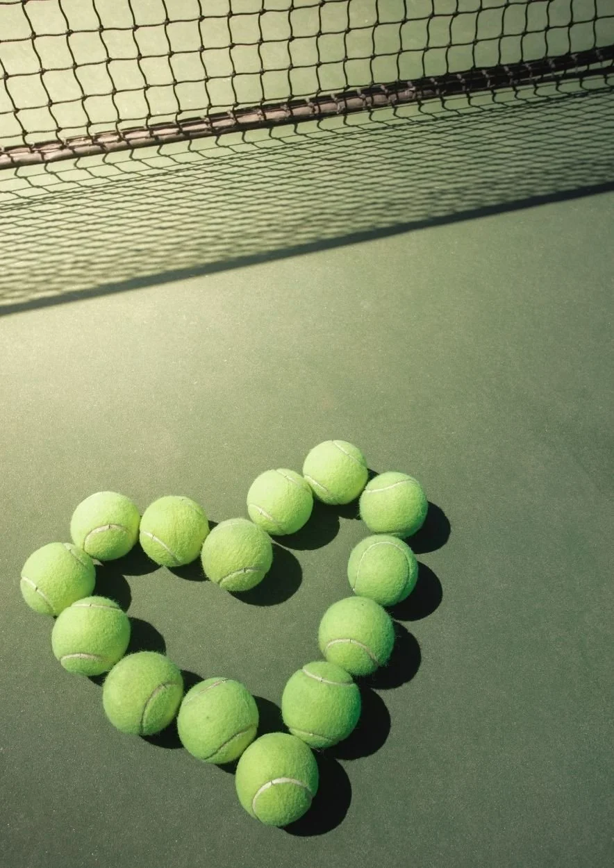Ball interaction sur un court de tennis, avec plusieurs balles de tennis formant un cœur, et un filet de tennis en arrière-plan.