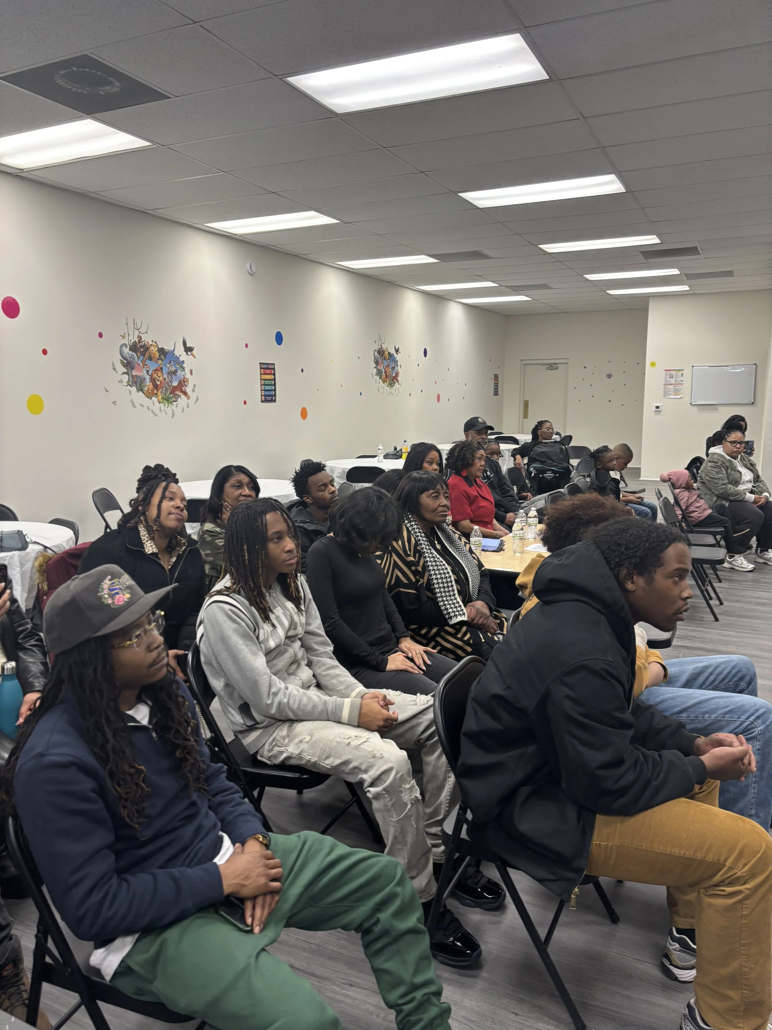 A group of diverse people seated in a conference room, attentively listening to a presentation or speaker.