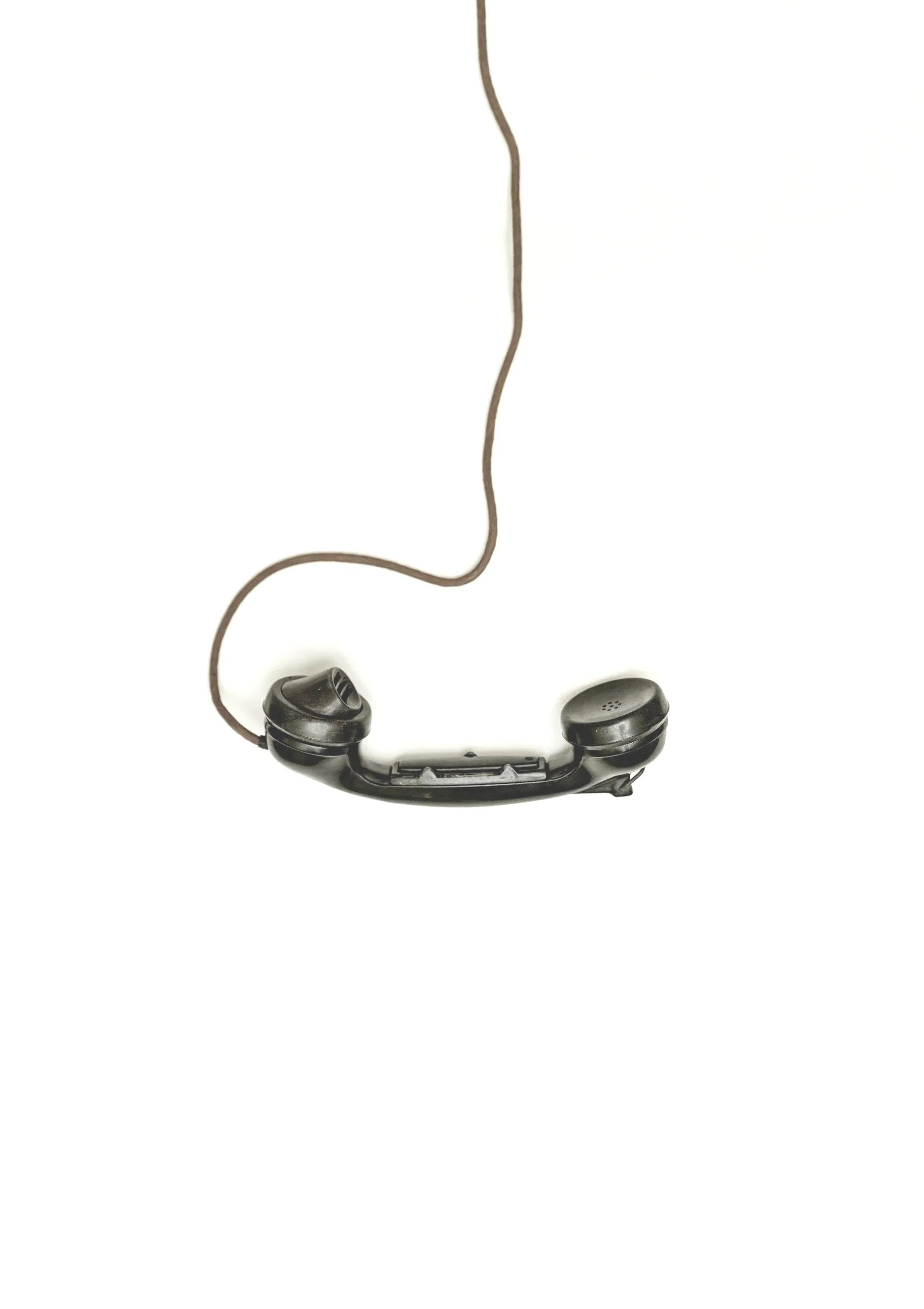 A pair of black wired earbuds with a long brown cable resting on a white background.