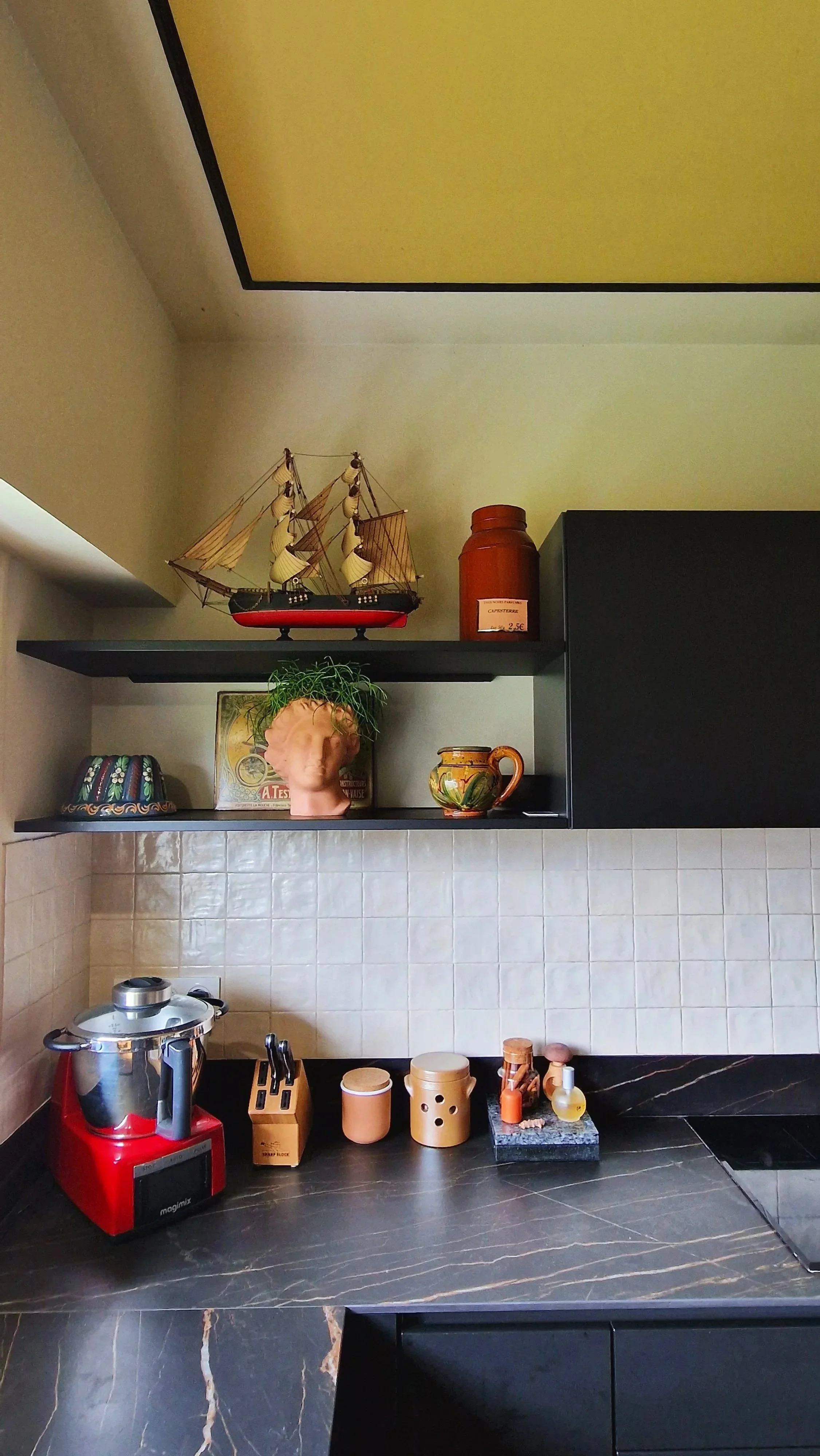 Une cuisine avec des étagères décoratives, des objets en céramique et une cuisinière électrique rouge.