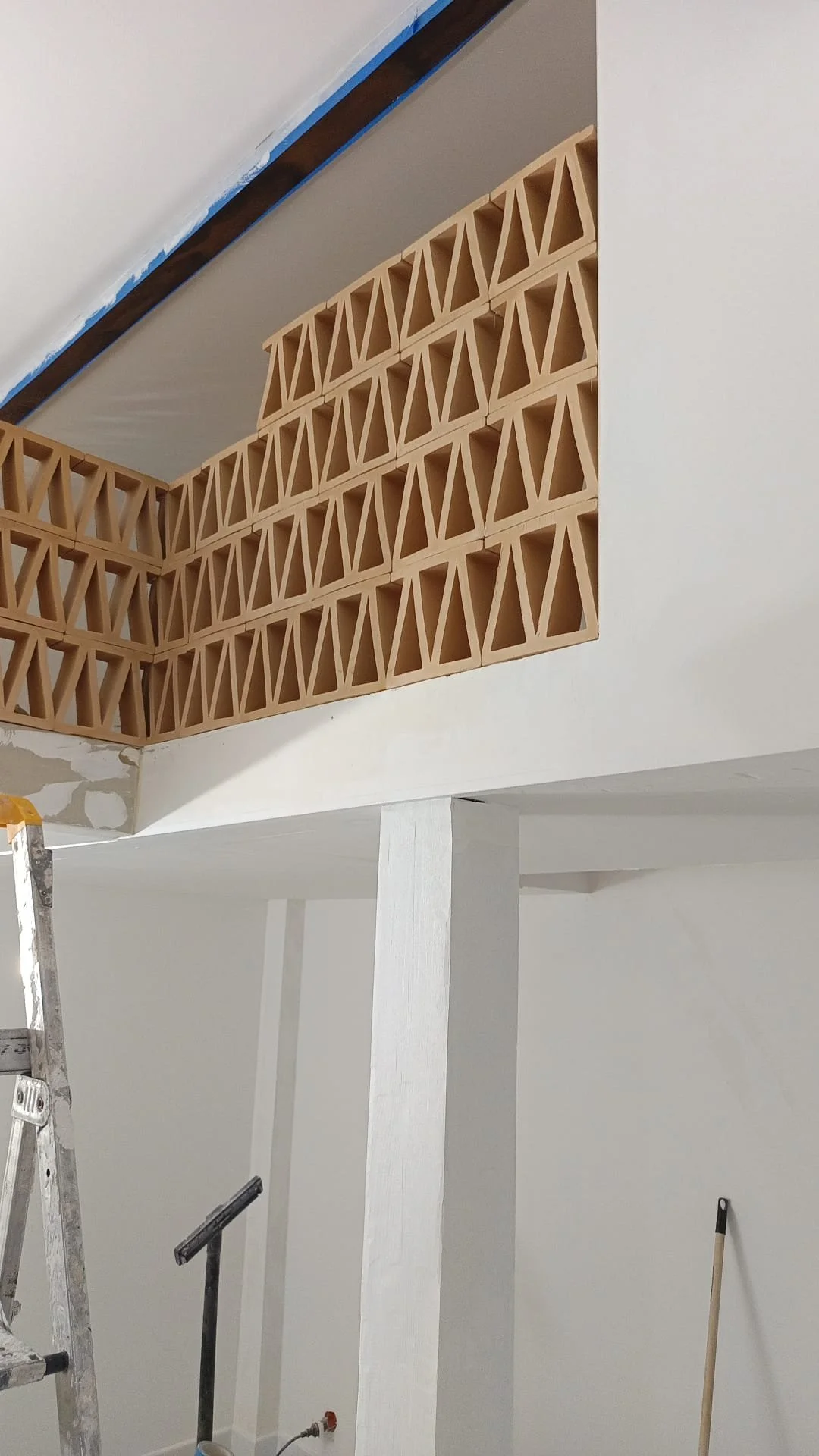 Travée en cours de construction avec des briques de terre cuite posées en hauteur à côté d'une colonne blanche.