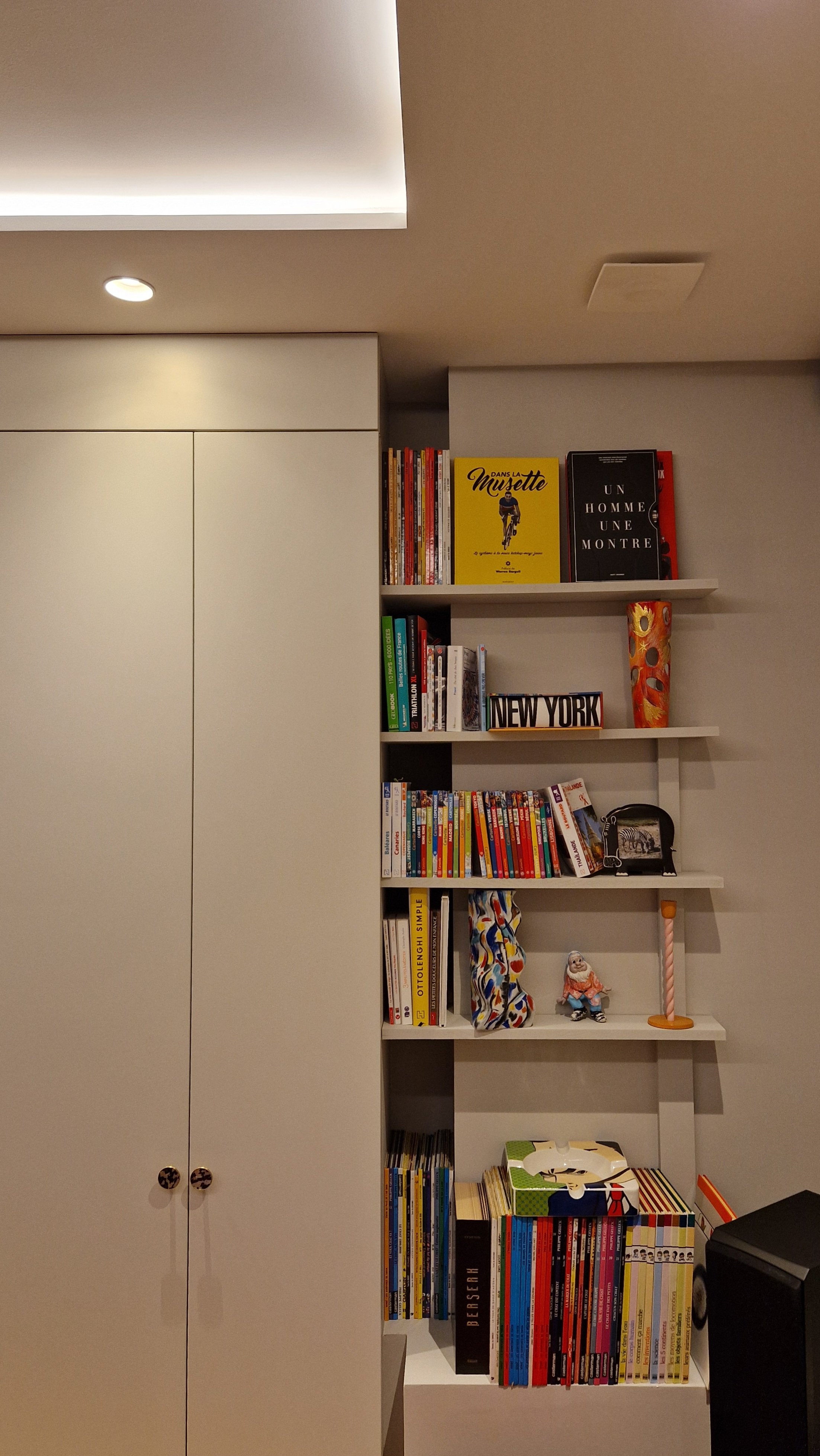 Bibliothèque avec livres, décorations, une figurine, une lampadaire et un ordinateur