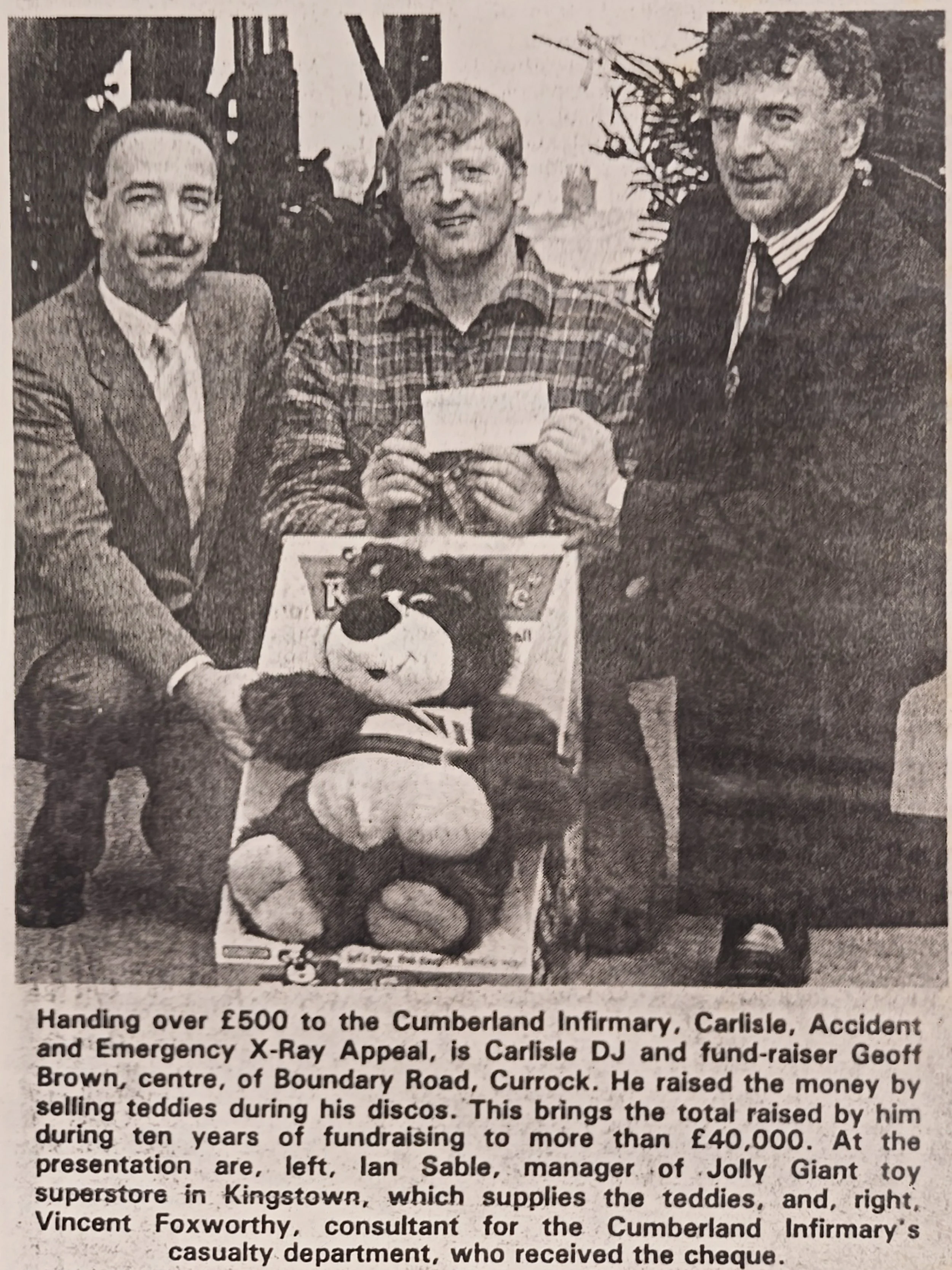 Black and white photo of three men standing behind a child dressed in a rugby unit and holding a teddy bear. The man in the middle is holding a cheque. The photo appears to be from a newspaper clipping with a caption about a fundraising event.