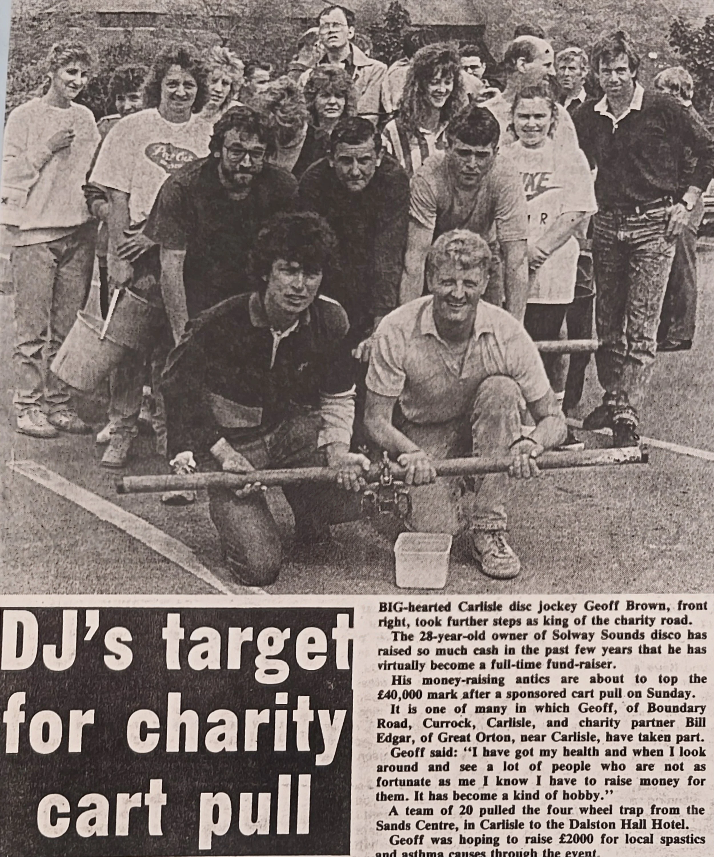 Black and white photo of a group of people, including a man in a sports jersey, gathered together outdoors, some holding a large check or donation box, appearing to participate in a charity event.