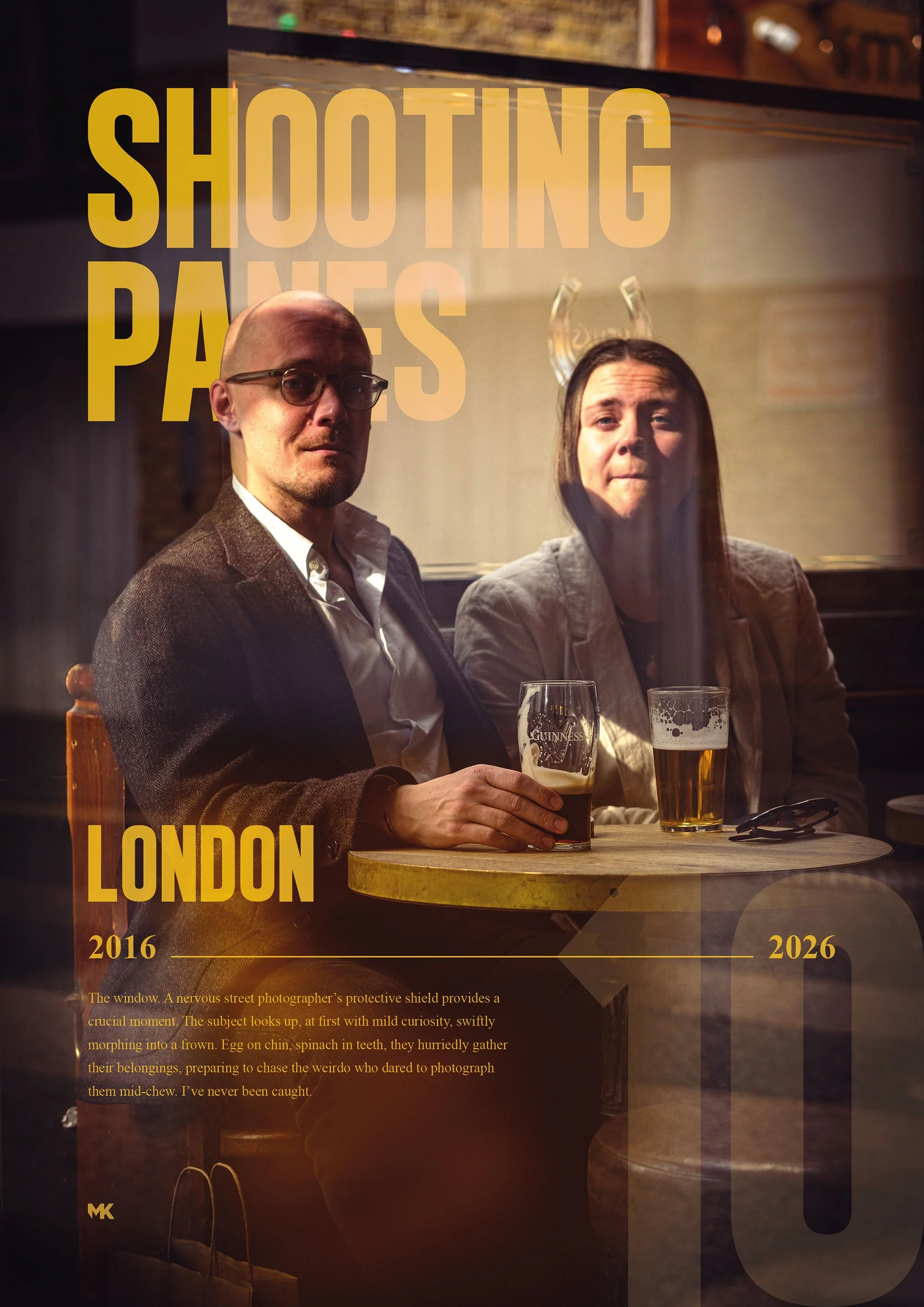 A photo of two people sitting at a round wooden table in a pub. The man on the left is bald, wearing glasses, a white shirt, and a brown blazer, holding a pint of Guinness beer. The woman on the right has long brown hair, wearing a light-colored jack
