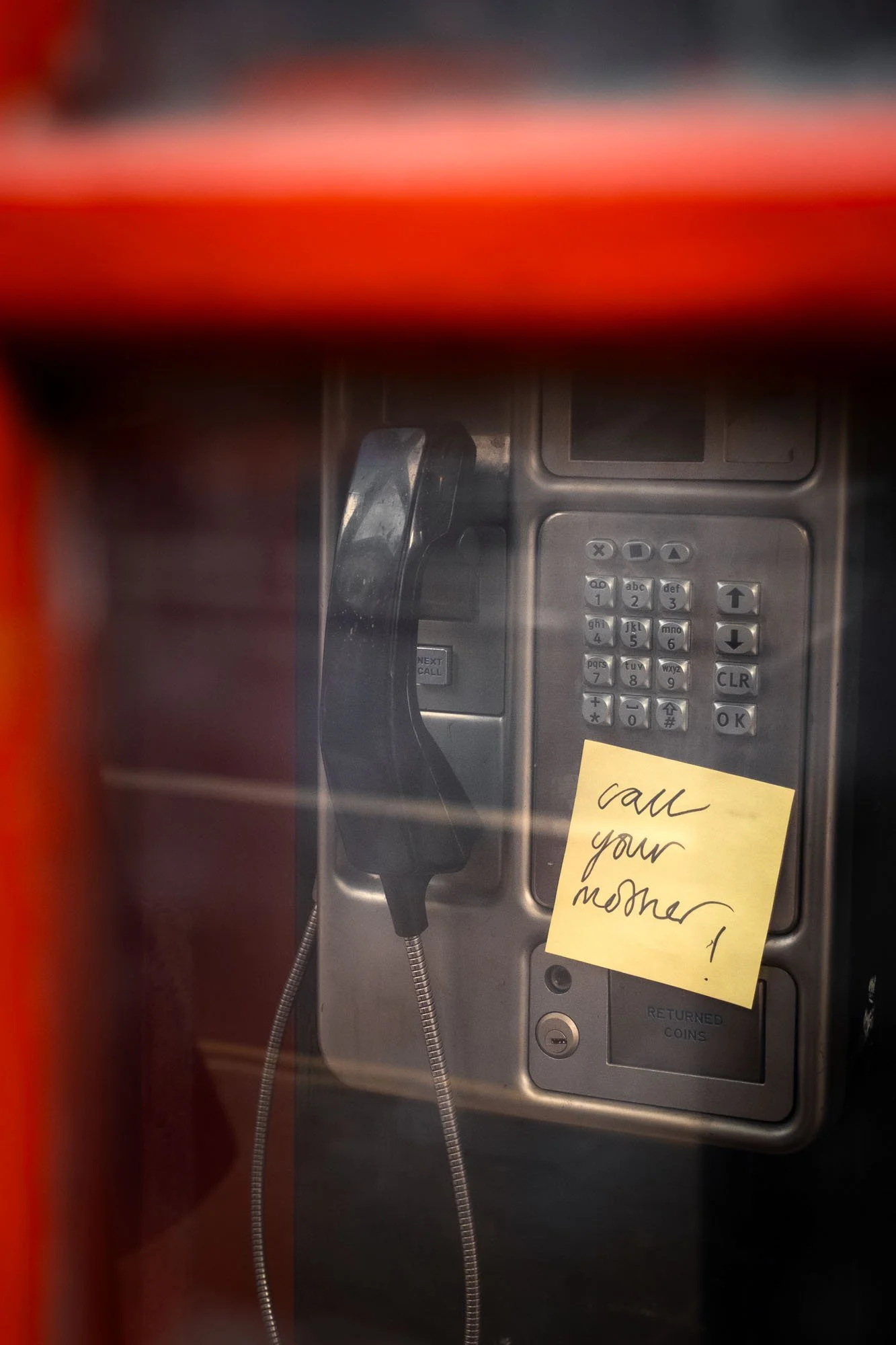Public payphone with a sticky note that says 'call your mother!'