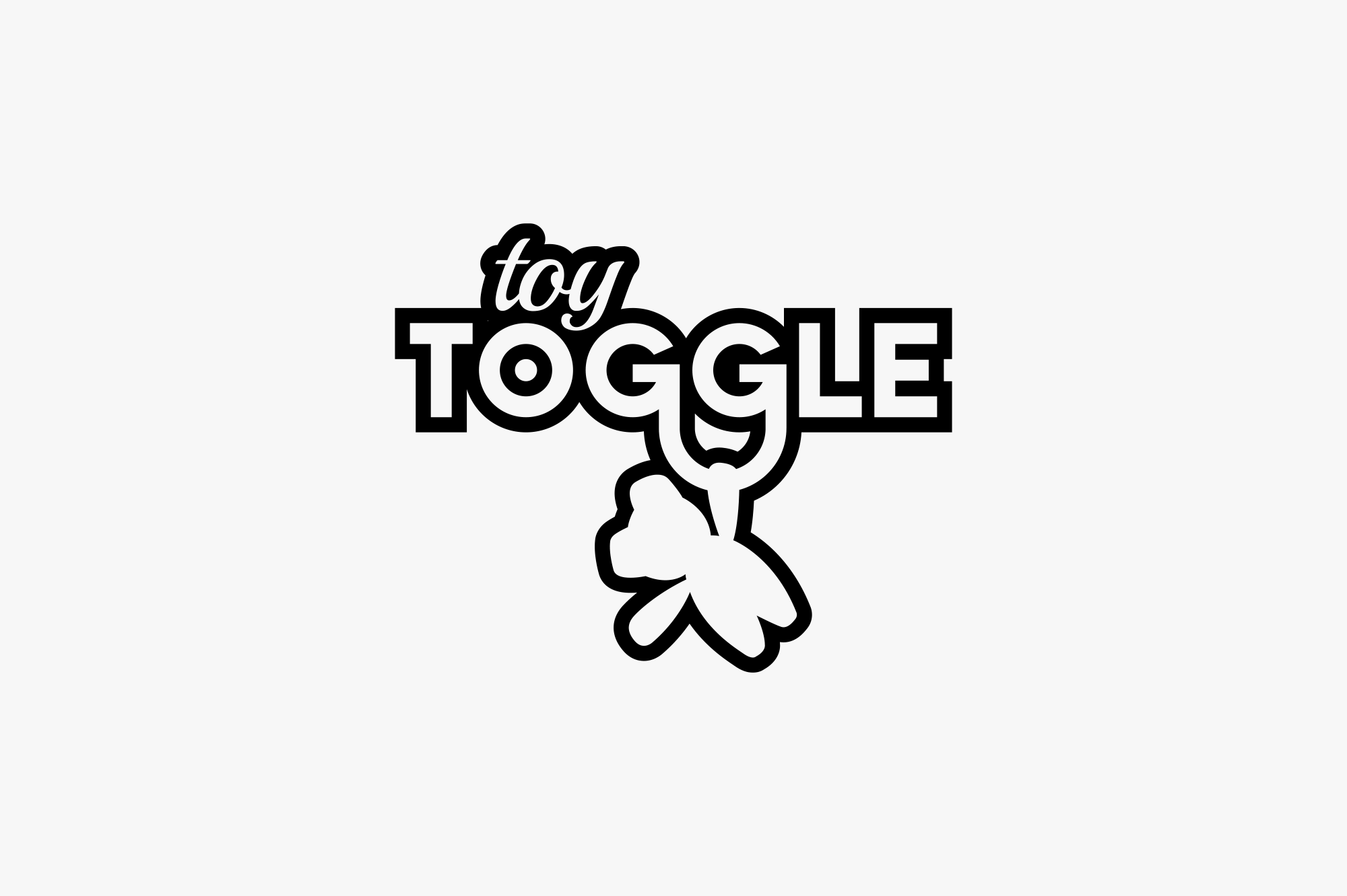 A black and white logo with the words "toy" and "TOGGLE" and a clover shape. The word "toy" is written in a small cursive font above the larger word "TOGGLE," which has a smiling face within the letter "O" and is adorned with a clover shape hanging b
