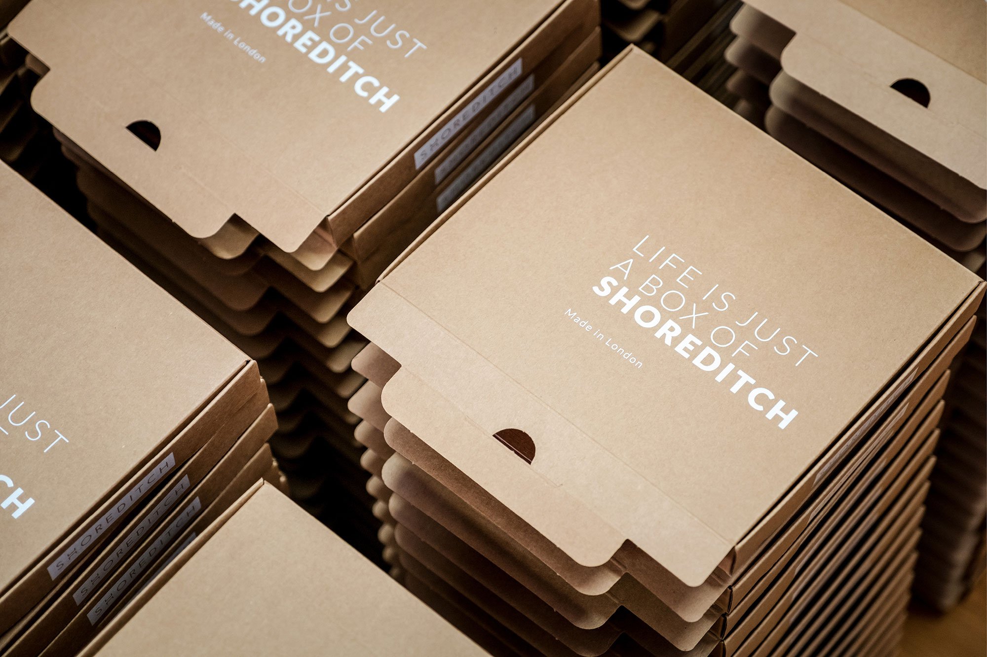 Several cardboard boxes with the text 'Life is just a box of shredded' printed on them, arranged in rows.